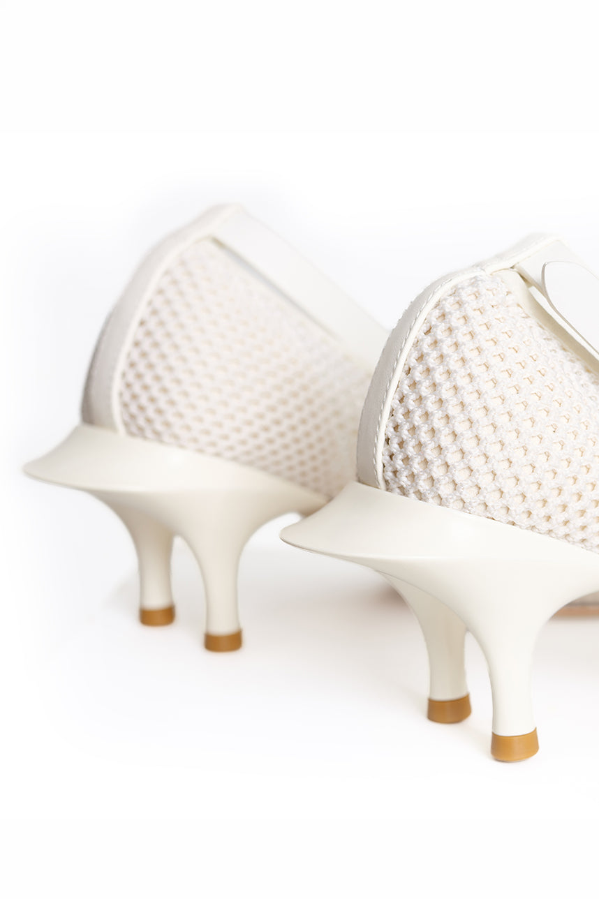 A close-up studio shot of a pair of white high-heeled shoes with textured mesh uppers and sculptural stiletto heels with tan soles, shown against a seamless white background.