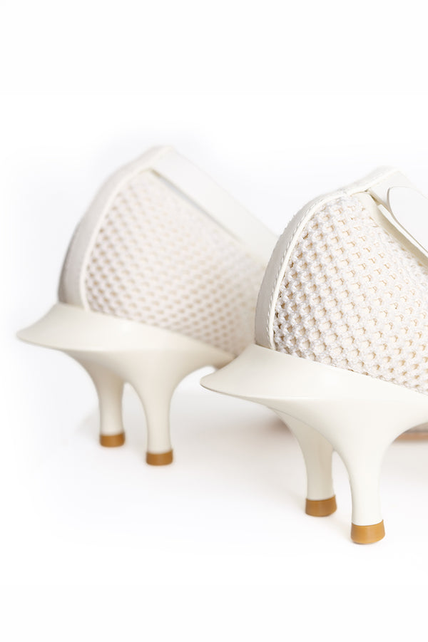 A close-up studio shot of a pair of white high-heeled shoes with textured mesh uppers and sculptural stiletto heels with tan soles, shown against a seamless white background.