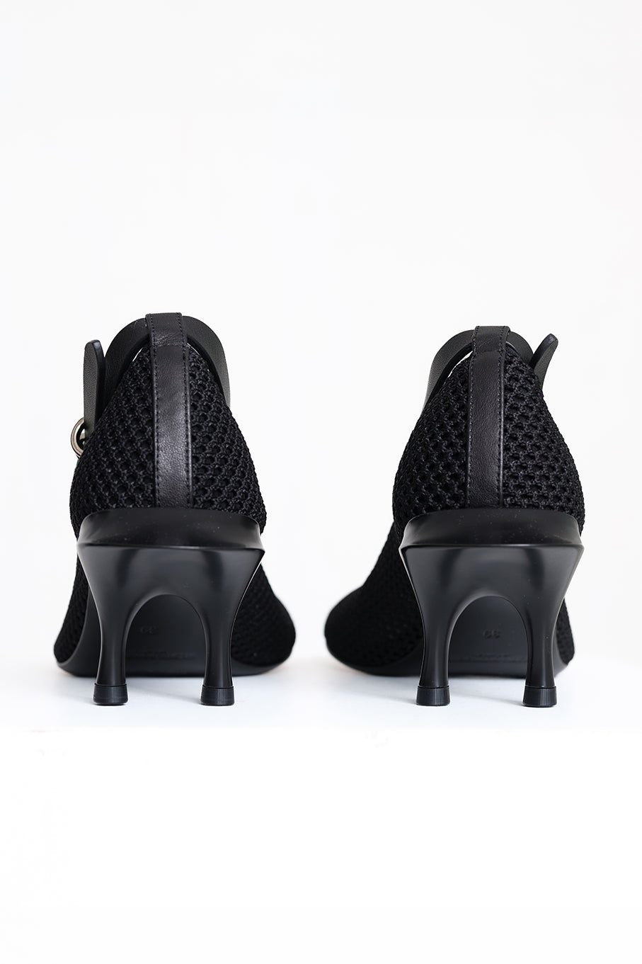 Black high-heeled ankle boots with a textured mesh upper and a side buckle strap, shown from the back against a white background.