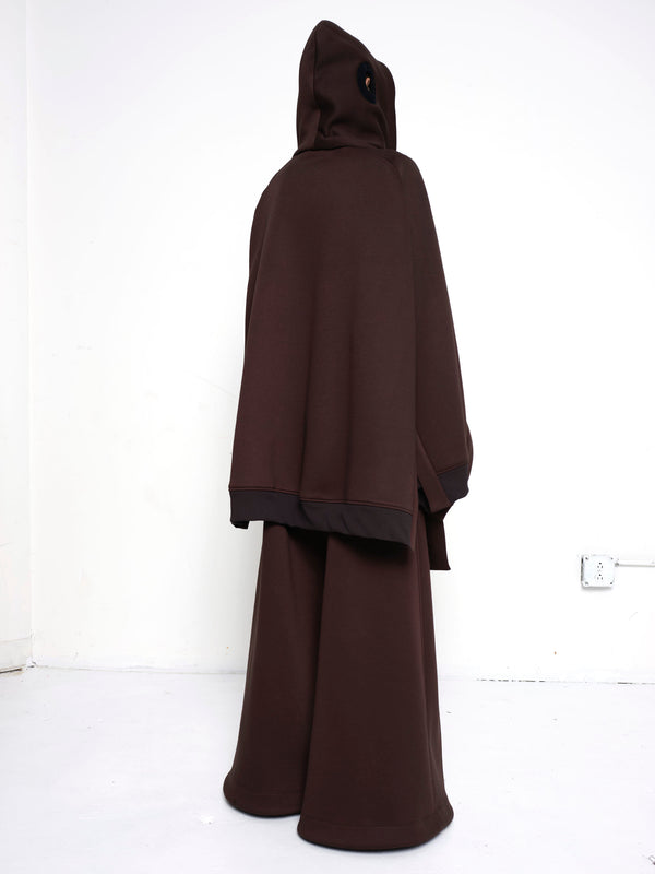 BRUNETTE-WOMAN-FROM-BACK-WEARING-BIG-ZIP-UP-HOODIE-BROWN-AND-TURTLENECK-ABOVE-NOSE-FULL-BODY-IMAGE-BROWN-PANTS-HOOD-ON