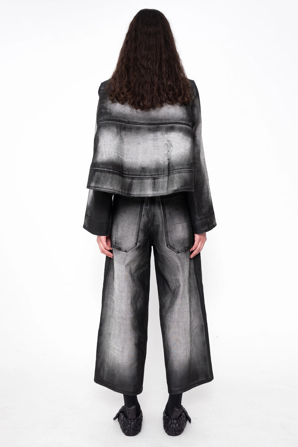 female-wearing-black-and-white-spray-painted-cropped-denim-shirt-with-foam-detail-at-hem-with-matching-cropped-denim-pants-on-white-background-full-body-back