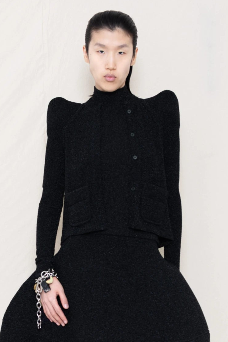 PERSON-WEARING-GLITTER-BLACK-FOAMY-SHOULDER-CARDIGAN-WITH-MATCHING-MOCK-NECK-SHIRT-AND-FOAMY-BALL-SKIRT-ACCESSORIZED-ON-THE-WRIST-MB-CHARM-BRACELET-CLOSE-UP-FRONT-VIEW