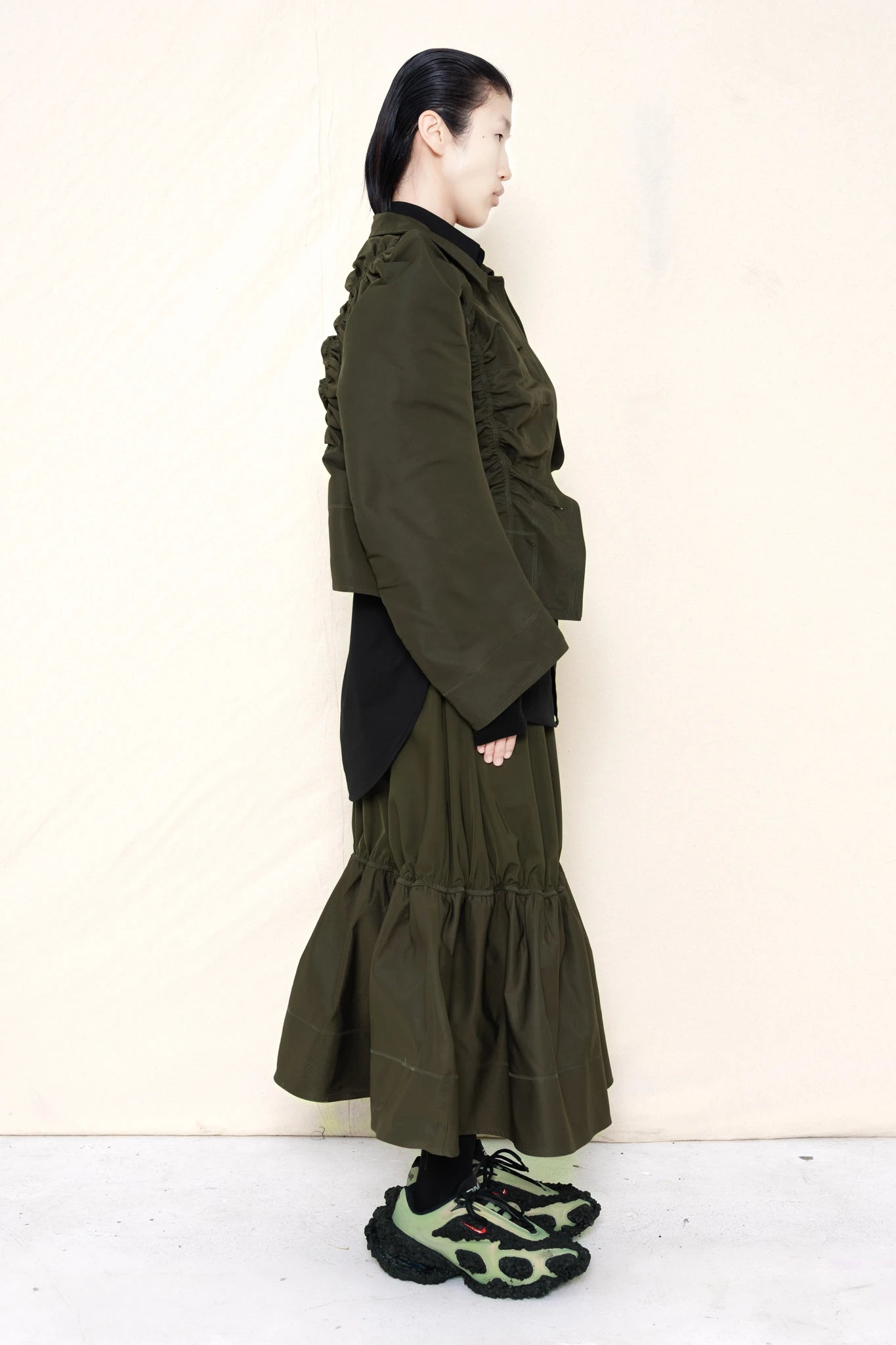 PERSON-WEARING-MOSS-RUCHED-JACKET-OVER-BLACK-BUTTON-DOWN-WITH-MOSS-RUCHED-SKIRT-AND-CUSTOMIZED-SNEAKERS-SIDE-VIEW