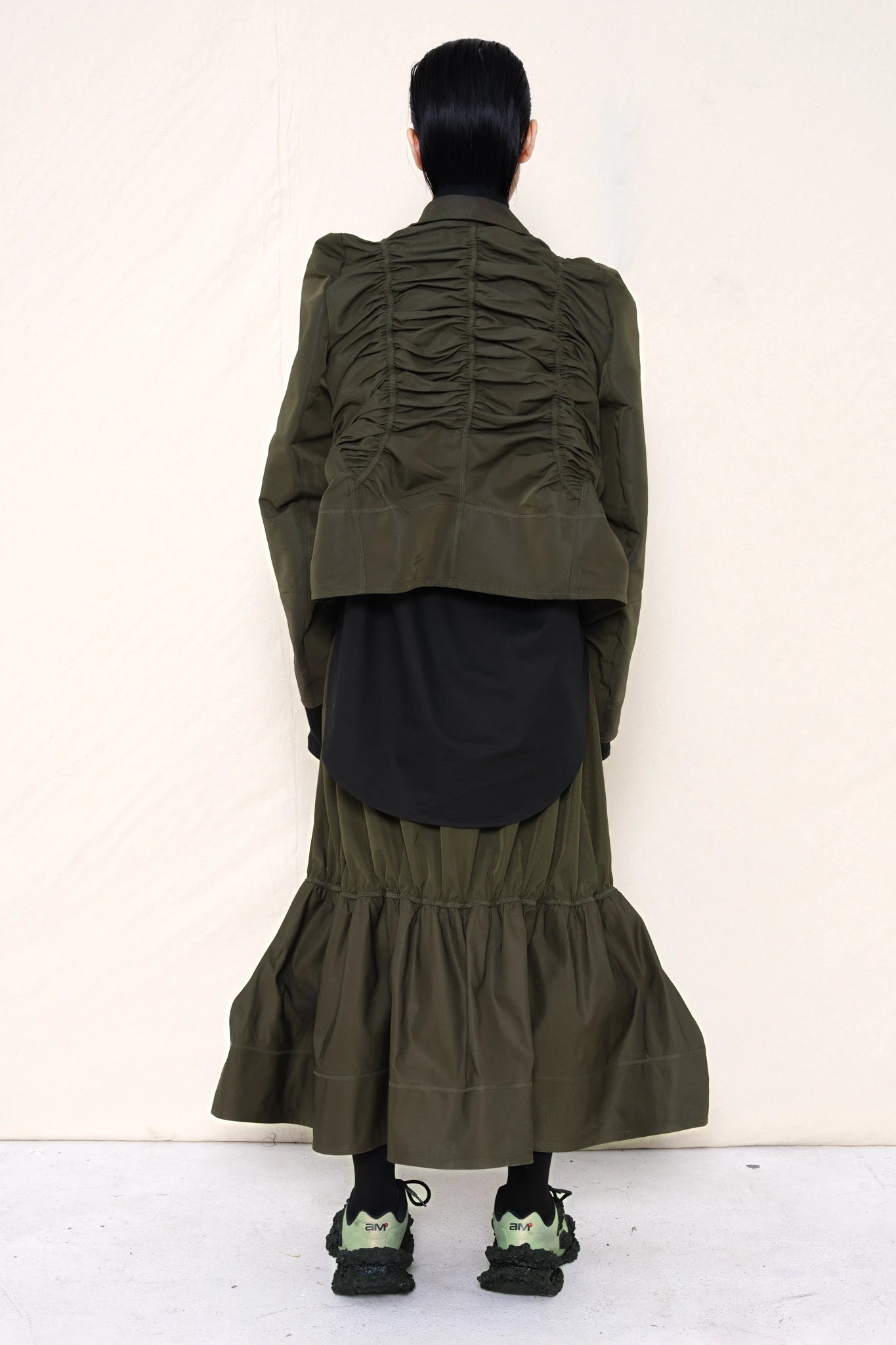 PERSON-WEARING-MOSS-RUCHED-JACKET-OVER-BLACK-BUTTON-DOWN-WITH-MOSS-RUCHED-SKIRT-AND-CUSTOMIZED-SNEAKERS-BACK-VIEW