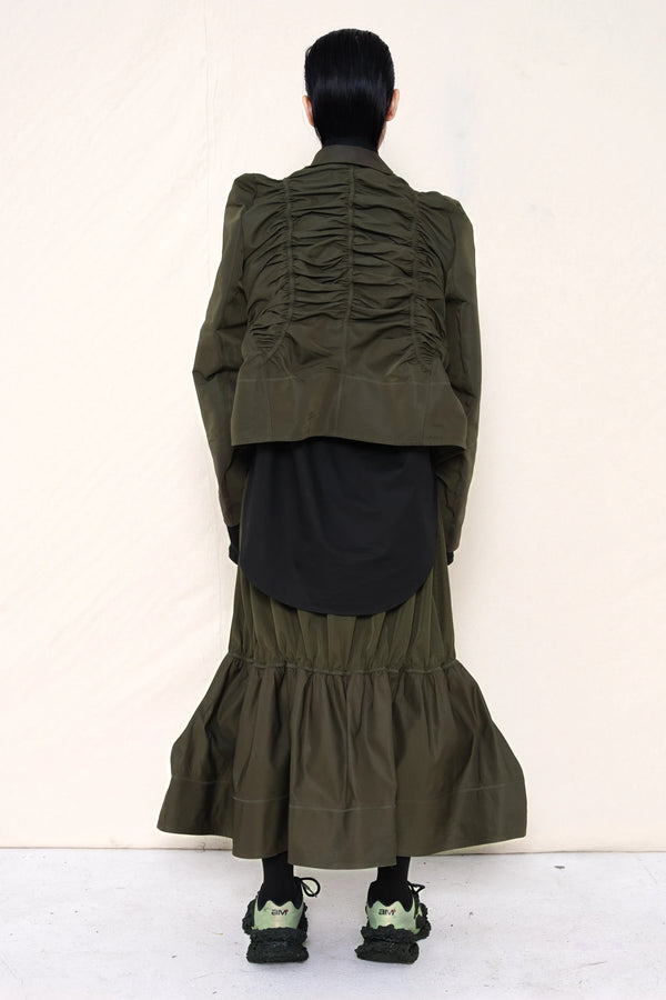 PERSON-WEARING-MOSS-RUCHED-JACKET-OVER-BLACK-BUTTON-DOWN-WITH-MOSS-RUCHED-SKIRT-AND-CUSTOMIZED-SNEAKERS-BACK-VIEW