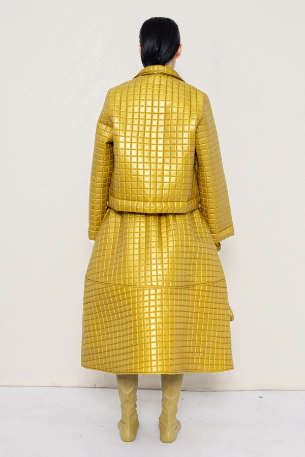PERSON-WEARING-GOLD-YELLOW-SLEEVE-MOCK-NECK-TOP-WITH-MATCHING-QUILTEDJACKET-WITH-COLLAR-AND-A-LINE-SKIRT-ACCESSORIZED-WITH-MB-CHARM-NECKLACE-AND-MUD-COLORED-POINTY-FLAT-BOOTS-HOLDING--MATCHING-BANANA-BAG-DETAIL-BACK-VIEW