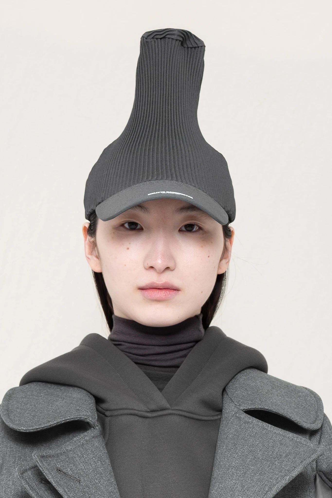 PERSON-WEARING-POINTY-PLEATED-COLD-GREY-CAP-CLOSE-UP-FRONT-VIEW