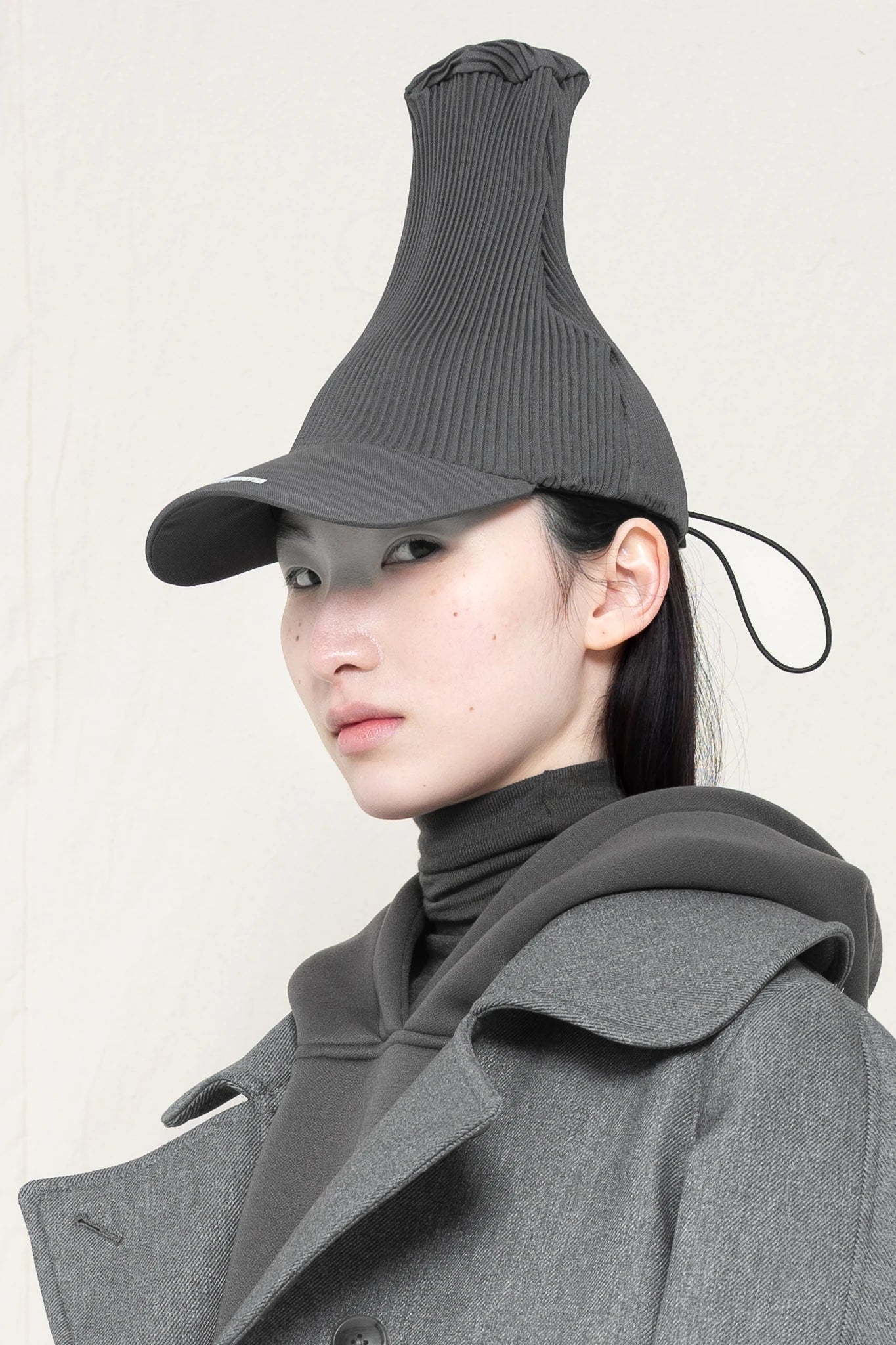PERSON-WEARING-POINTY-PLEATED-COLD-GREY-CAP-CLOSE-UP-THREE-QUARTER-VIEW
