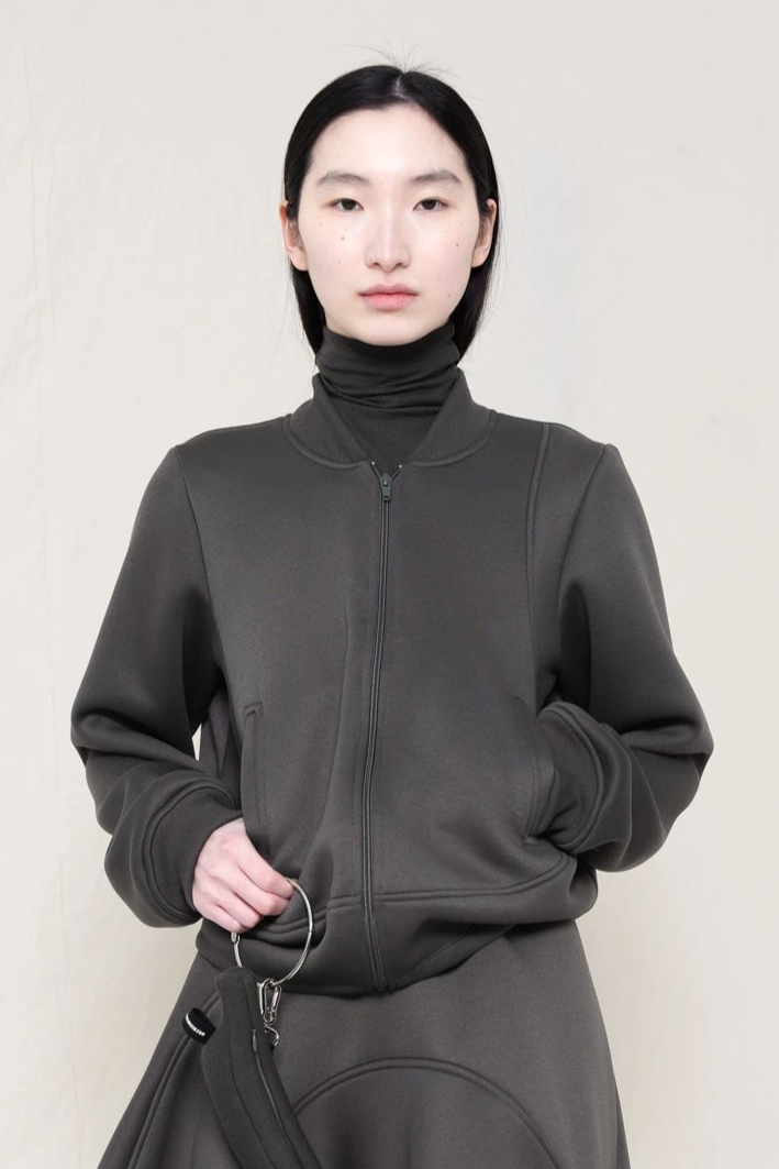 PERSON-WEARING-STONE-GREY-WAVY-ZIP-UP-WITH-MATCHING-WAVY-SEAM-SKIRT-HOLDING-GREY-BANANA-TOTE-BAG-CLOSE-UP-FRONT-VIEW