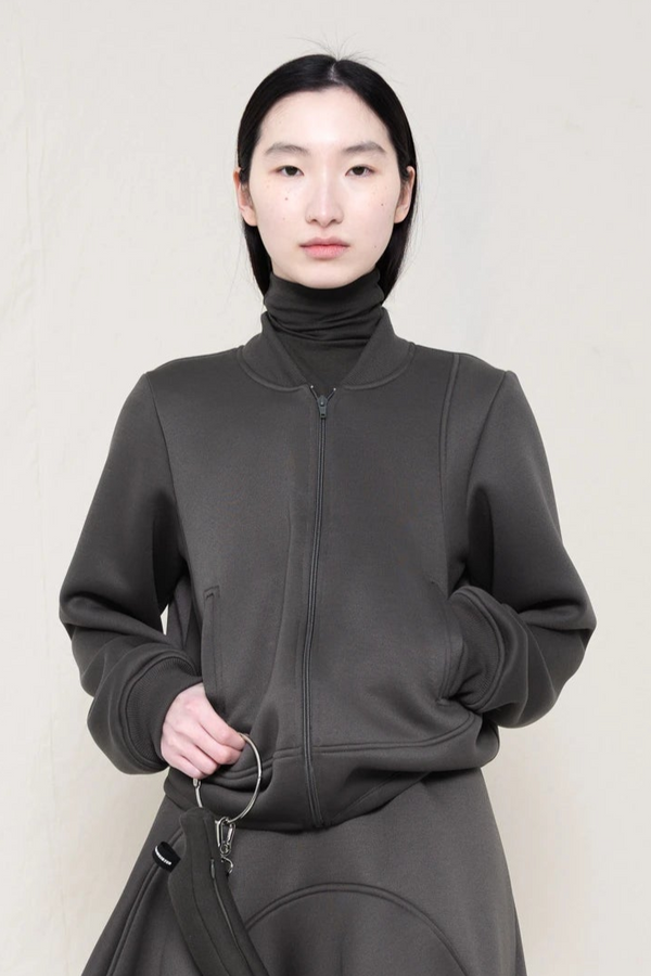 PERSON-WEARING-STONE-GREY-WAVY-ZIP-UP-WITH-MATCHING-WAVY-SEAM-SKIRT-HOLDING-GREY-BANANA-TOTE-BAG-CLOSE-UP-FRONT-VIEW