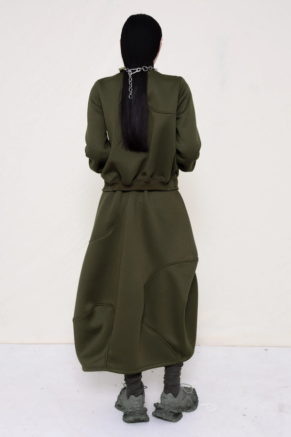 PERSON-WEARING-MOSS-WAVY-ZIP-UP-WITH-MATCHING-WAVY-SEAM-SKIRT-ACCESSORIZED-WITH-MB-CHARM-NECKLACE-AND-CUSTOMIZED-SNEAKERS-BACK-VIEW