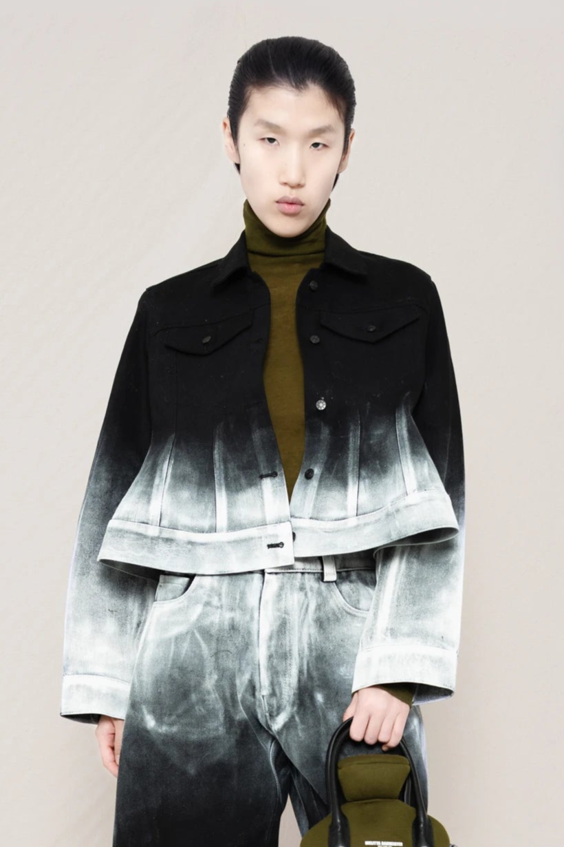 PERSON-WEARING-CROPPED-WHITE-OMBRE-PAINTED-BLACK-PANTS-AND-JACKET-HOLDING-MOSS-HOT-WATER-BOTTLE-SHAPED-BAG-CLOSE-UP-FRONT-VIEW