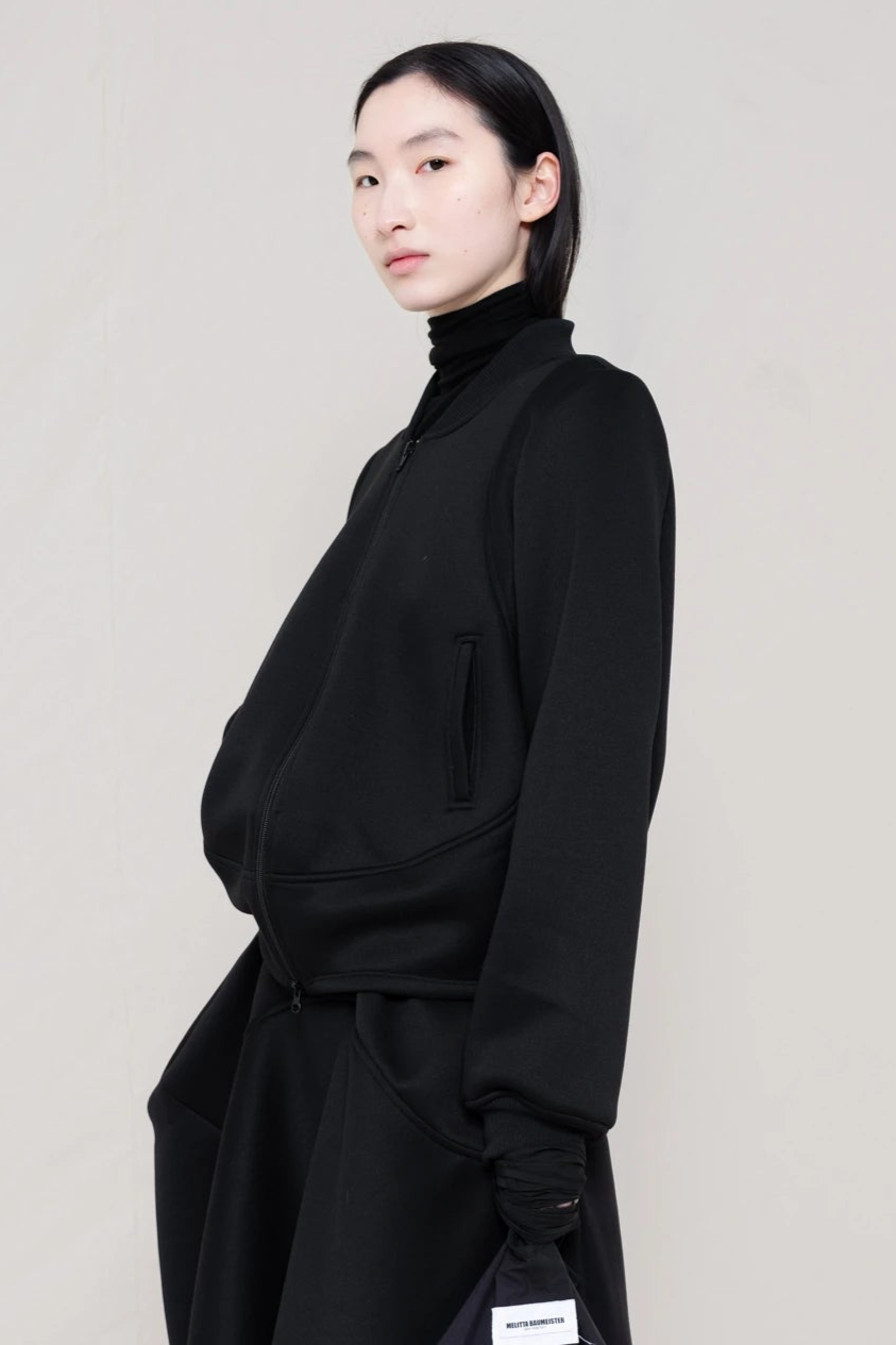 PERSON-WEARING-BLACK-WAVY-ZIP-UP-WITH-MATCHING-WAVY-SEAM-SKIRT-CLOSE-UP-THREE-QUARTER-VIEW