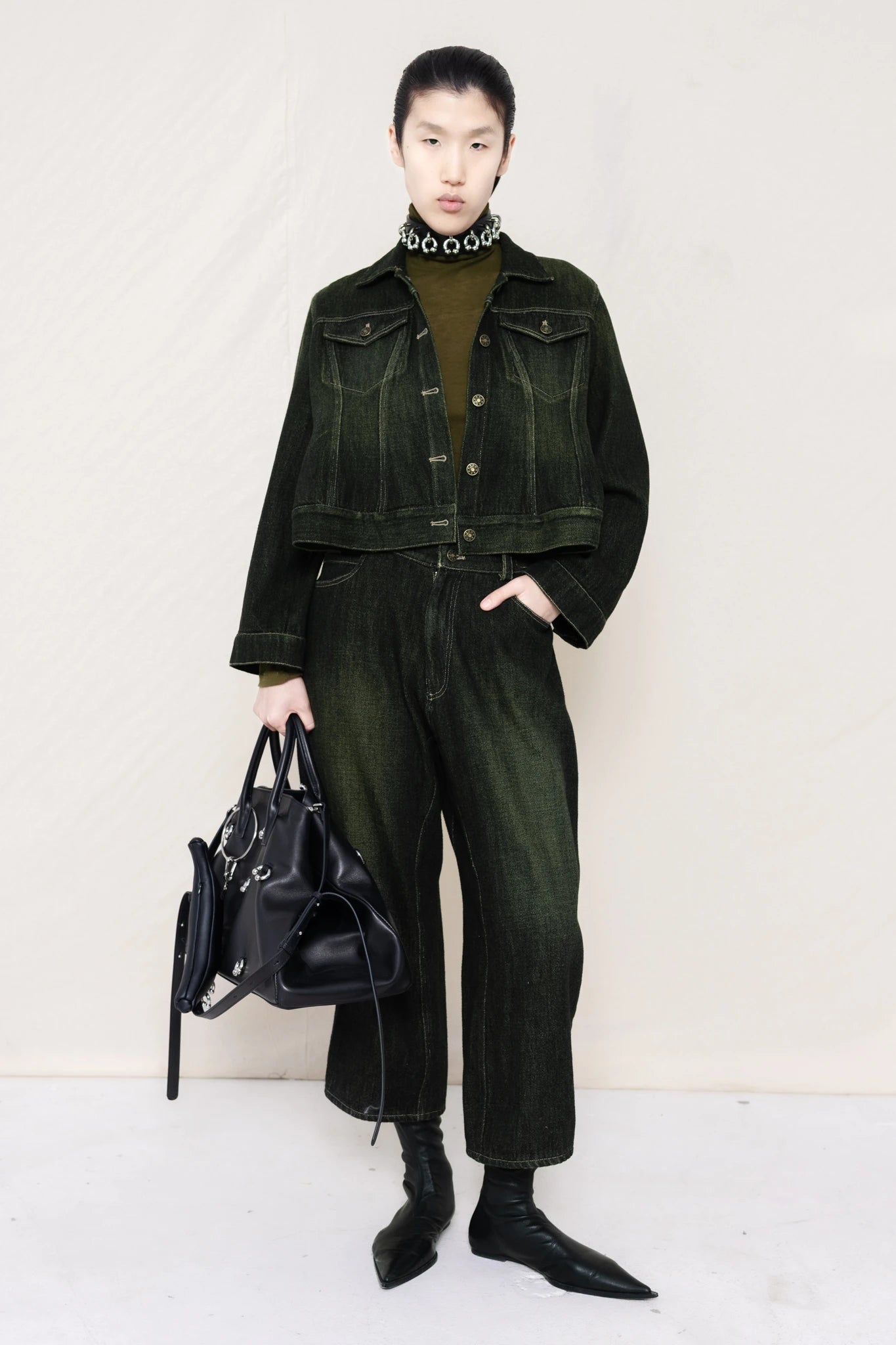 PERSON-WEARING-PIERCED-CHOKER-ON-MOSS-LONG-SLEEVE-TURTLENECK-UNDER-CROPPED-BLACK-YELLOW-WASH-SOFT-DENIM-JACKET-WITH-MATCHING-PANTS-HOLDING-A-LINE-SHOPPER-FRONT-VIEW