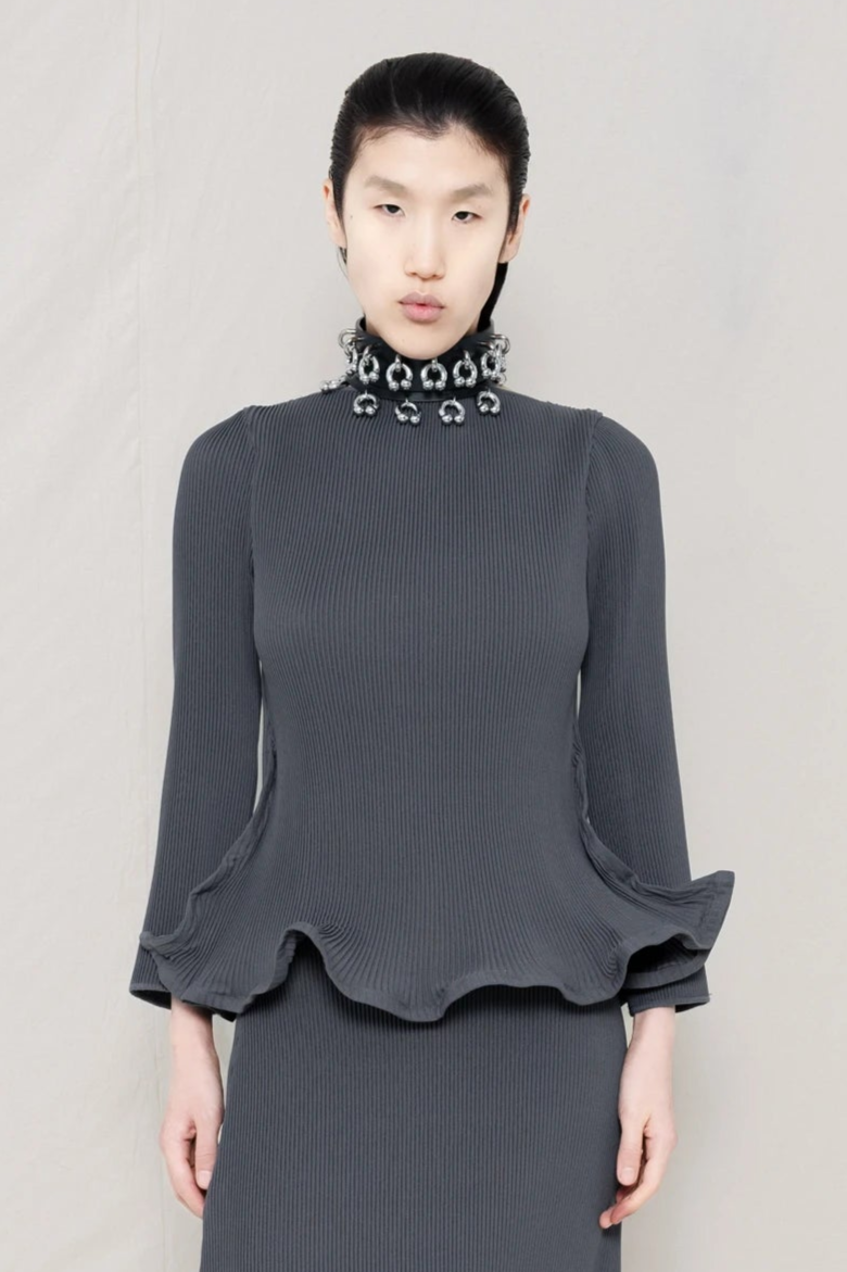 PERSON-WEARING-COLD-GREY-RIPPLE-PLEAT-ZIG-ZAG-HEM-TOP-AND-MATCHING-RIPPLE-PLEAT-ZIG-ZAG-HEM-SKIRT-ACCESSORIZED-WITH-PIERCED-CHOKER-CLOSE-UP-FRONT-VIEW