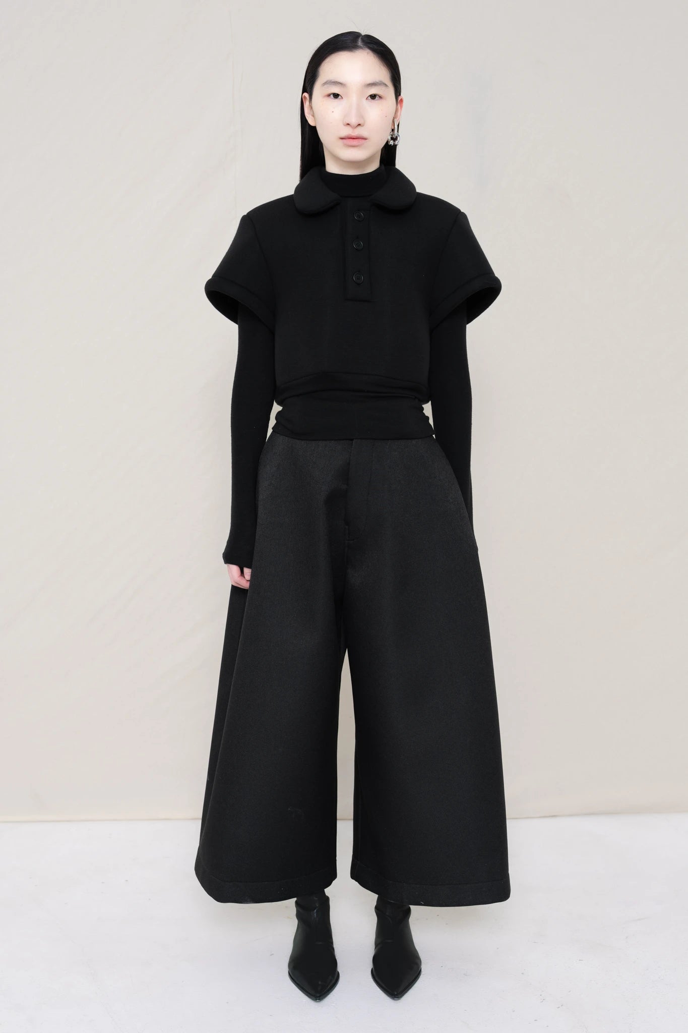 women-wearing-a-black-cropped-extremely-spongy-polo-shirt-over-a-black-turle-neck-worn-with-black-spongy-WIDE-LEG-TAILORED-WAIS-CULOTTE-PANT-paired-with-balck-pointed-leather-boots-full-body-front-view