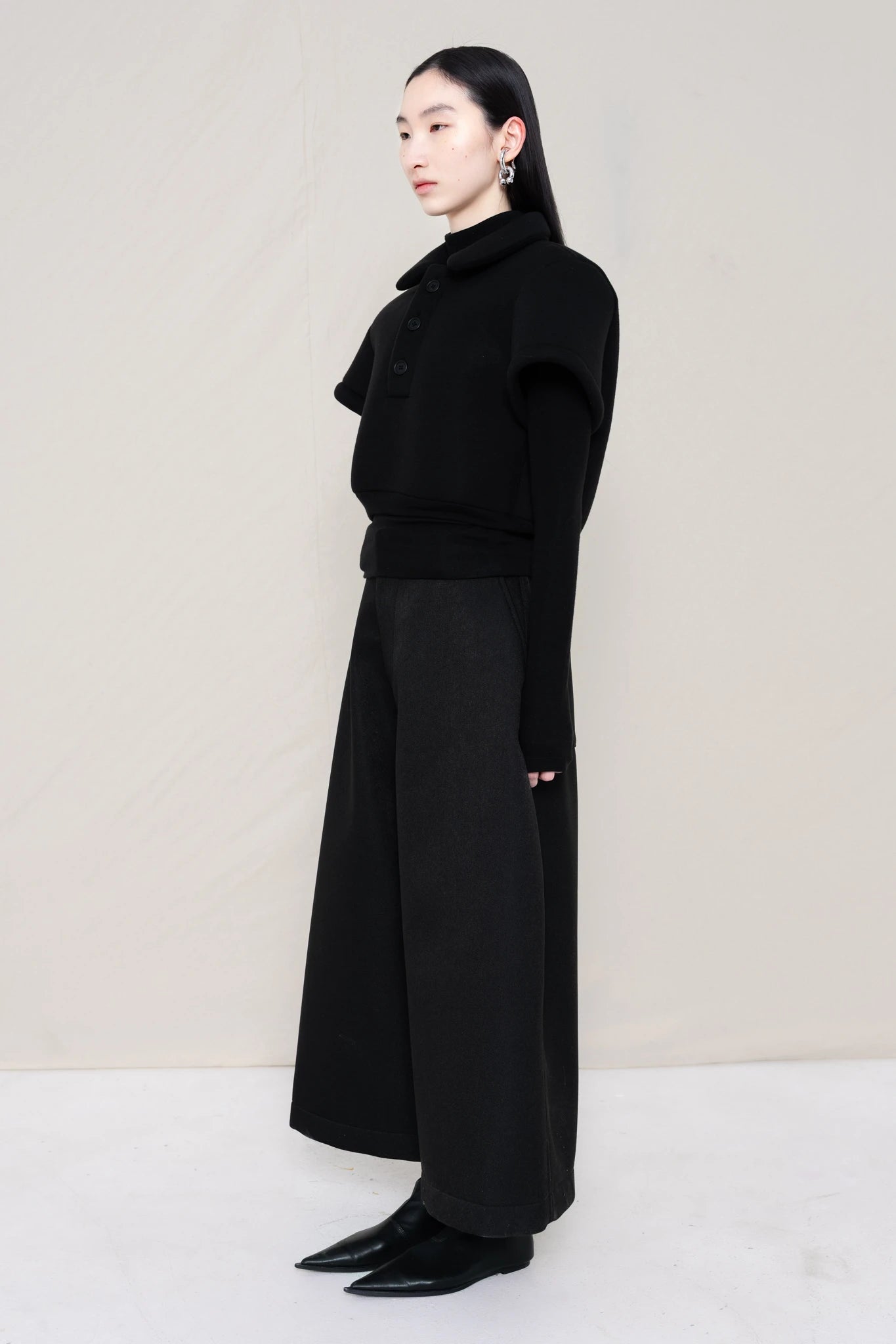 PERSON-WEARING-BLACK-FOAMY-POLO-WITH-BLACK-LONG-SLEEVE-TURTLENECK-UNDER-AND-BLACK-CULOTTES-WITH-BLACK-FLAT-POINTY-BOOTS-THREE-QUARTER-VIEW