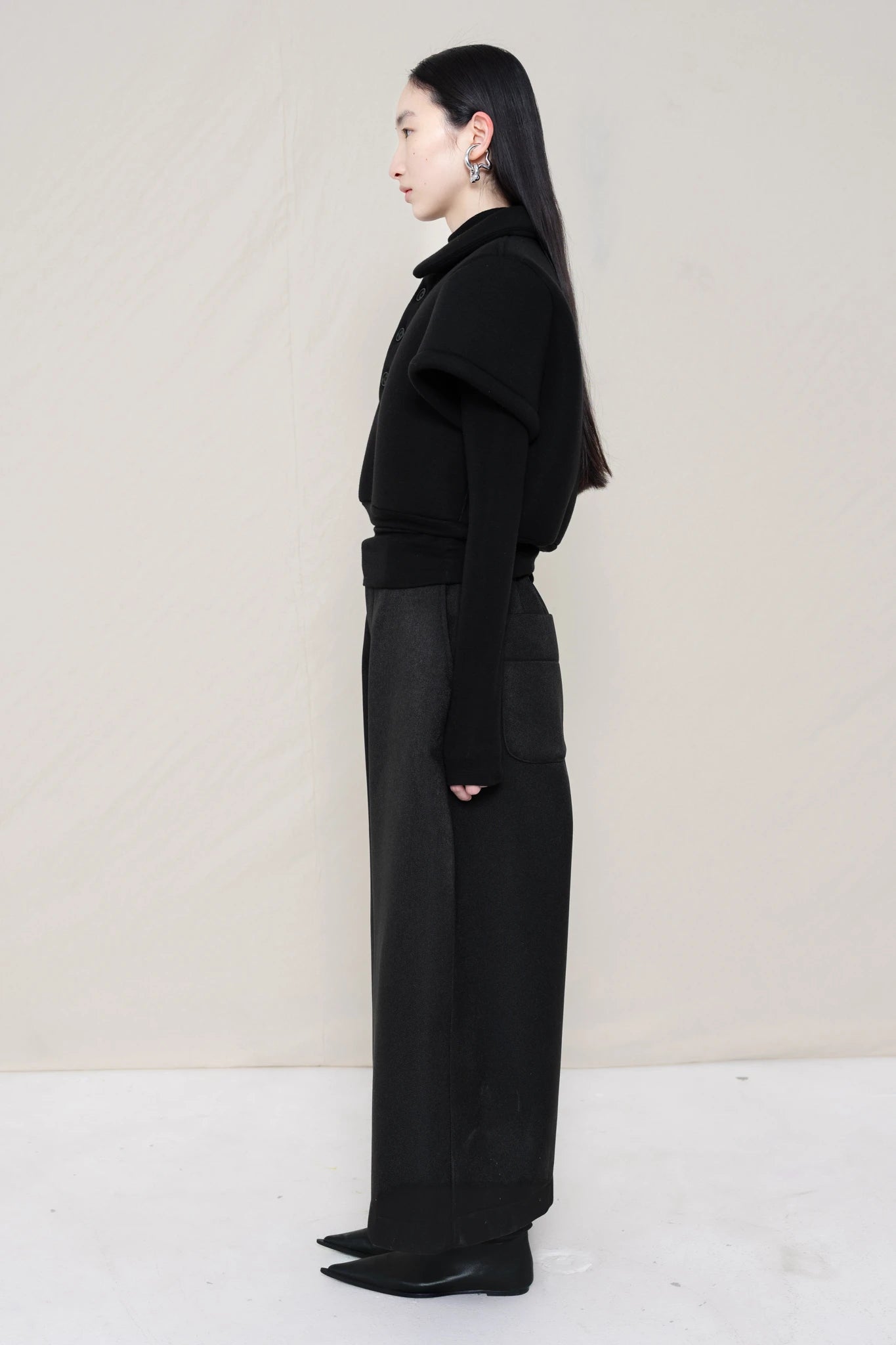 women-wearing-a-black-cropped-extremely-spongy-polo-shirt-over-a-black-turle-neck-worn-with-black-spongy-WIDE-LEG-TAILORED-WAIS-CULOTTE-PANT-paired-with-balck-pointed-leather-boots-full-body-side-view