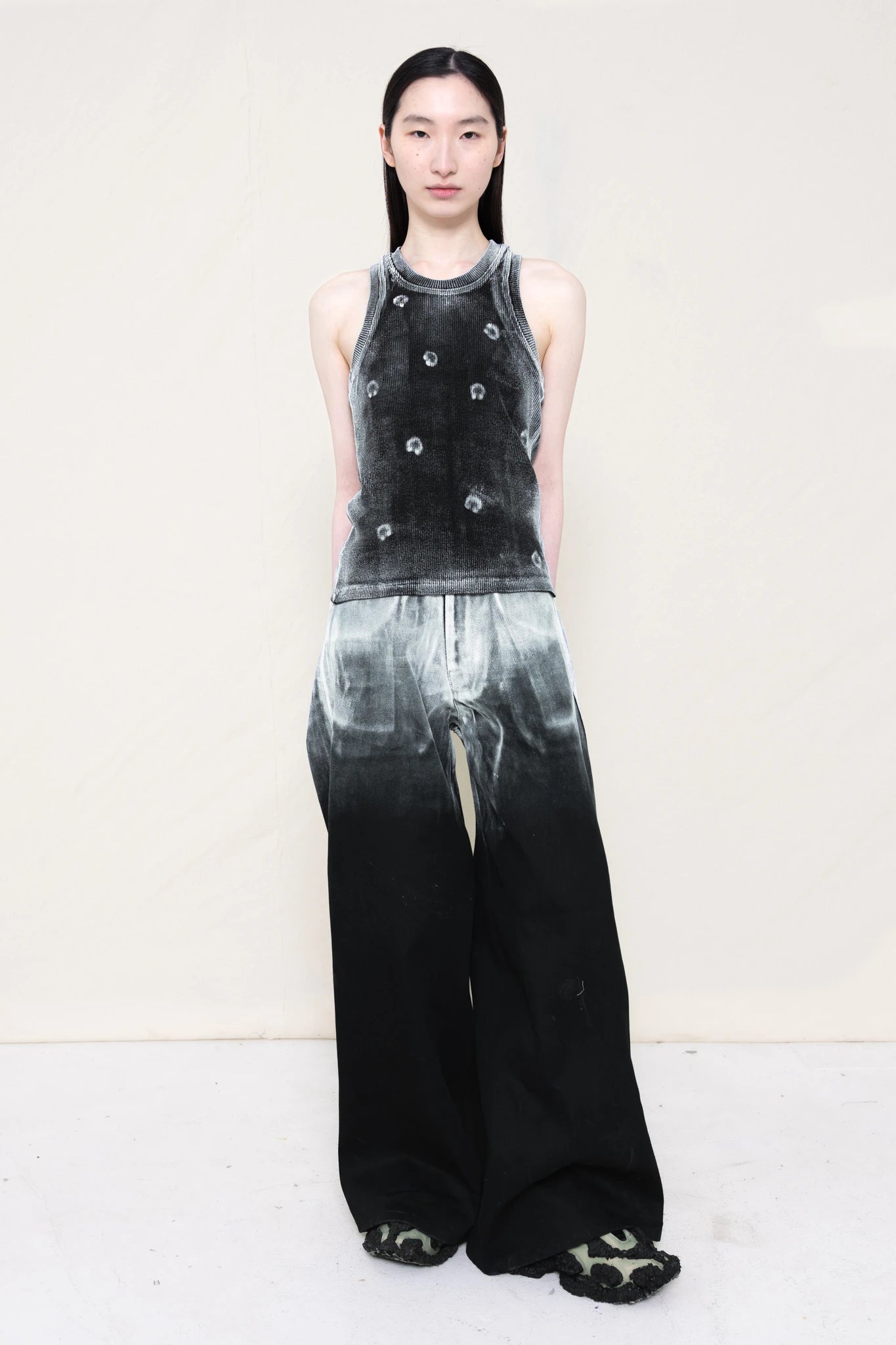 PERSON-WEARING-LONG-PAINTED-DENIM-PANTS-WITH-PAINTED-PIERCING-TANK-TOP-AND-CUSTOMIZED-SNEAKERS-FRONT-VIEW