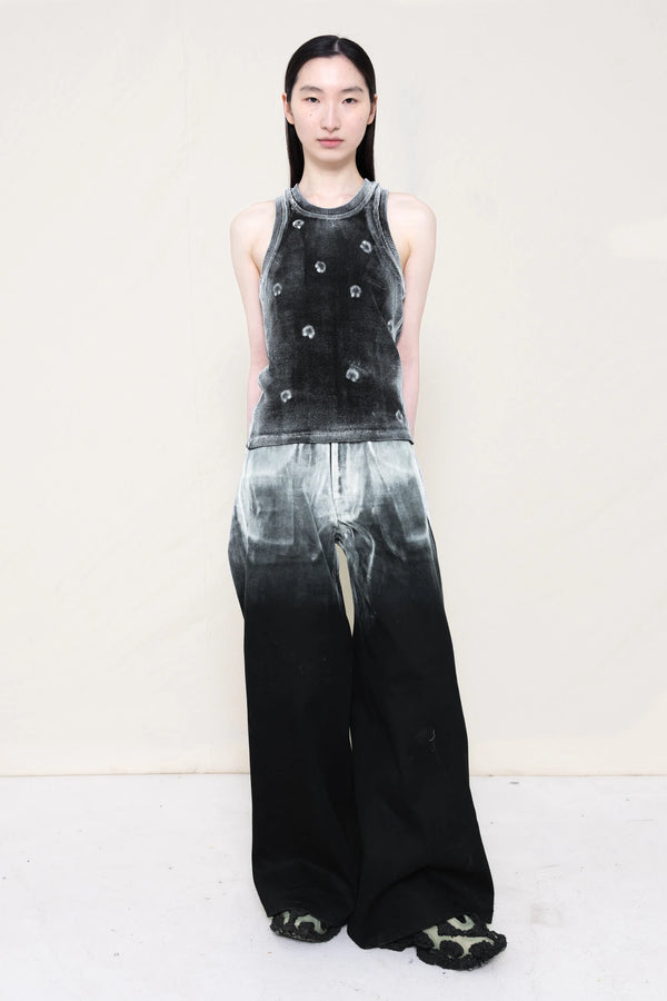 PERSON-WEARING-LONG-PAINTED-DENIM-PANTS-WITH-PAINTED-PIERCING-TANK-TOP-AND-CUSTOMIZED-SNEAKERS-FRONT-VIEW