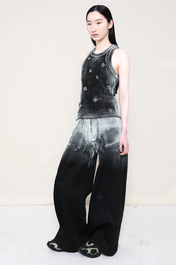PERSON-WEARING-LONG-PAINTED-DENIM-PANTS-WITH-PAINTED-PIERCING-TANK-TOP-AND-CUSTOMIZED-SNEAKERS-THREE-QUARTER-VIEW