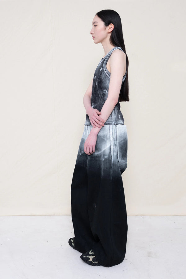 PERSON-WEARING-LONG-PAINTED-DENIM-PANTS-WITH-PAINTED-PIERCING-TANK-TOP-AND-CUSTOMIZED-SNEAKERS-SIDE-VIEW