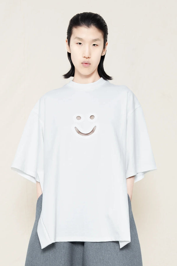 PERSON-WEARING-WHITE-TEE-WITH-SMILEY-CUT-OUT-AND-SIDE-SLIT-DETAIL-PAIRED-WITH-MELANGE-WIDE-LEG-TAILORED-WAIST-CULOTTES-AND-CUSTOMIZED-SNEAKERS-SIDE-VIEW