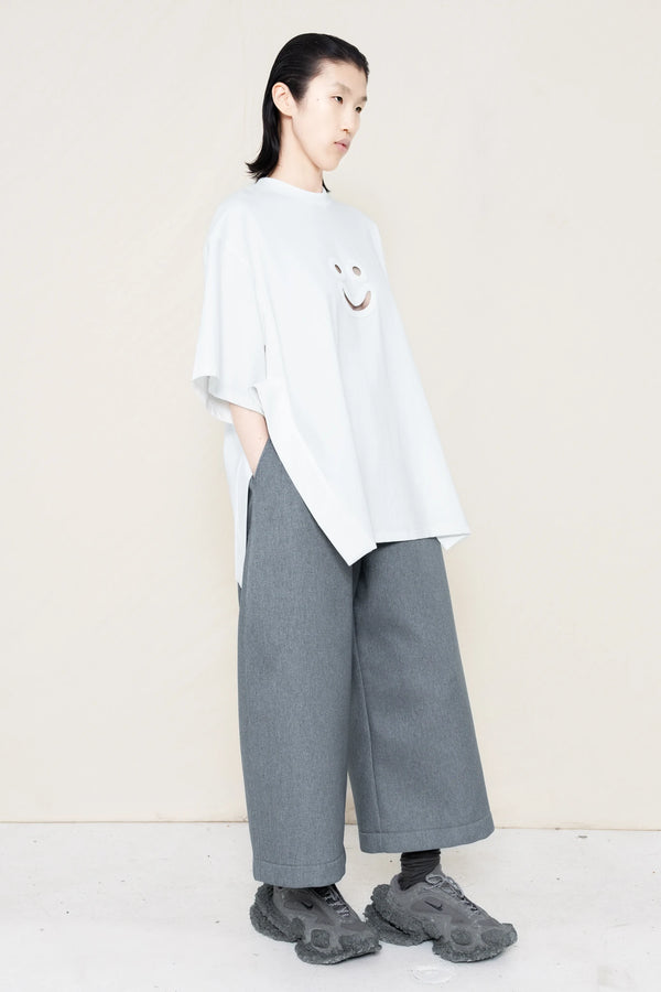 PERSON-WEARING-WHITE-TEE-WITH-SMILEY-CUT-OUT-AND-SIDE-SLIT-DETAIL-PAIRED-WITH-MELANGE-WIDE-LEG-TAILORED-WAIST-CULOTTES-AND-CUSTOMIZED-SNEAKERS-three-quarters-VIEW