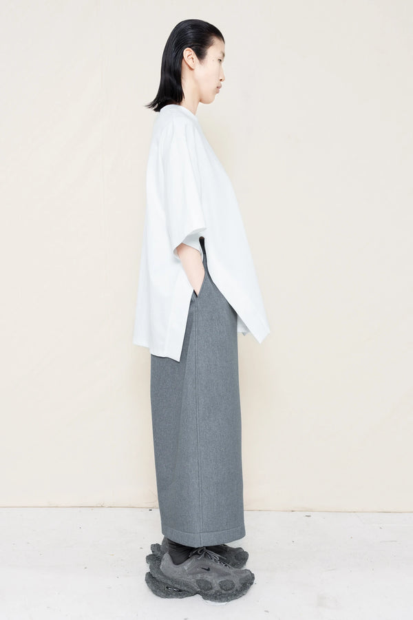 PERSON-WEARING-WHITE-TEE-WITH-SMILEY-CUT-OUT-AND-SIDE-SLIT-DETAIL-PAIRED-WITH-MELANGE-WIDE-LEG-TAILORED-WAIST-CULOTTES-AND-CUSTOMIZED-SNEAKERS-SIDE-VIEW