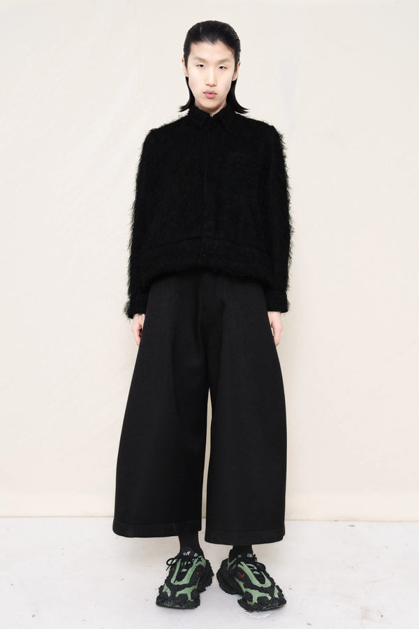 Man-wearing-A-black-COLLARED-HAIRY-JACQUARD-BUTTON-DOWN-WITH-FOAM-BOTTOM-DETAIL-over-wide-black-trousers-and-custom-shoes-against-a-plain-background-full-body-front-view