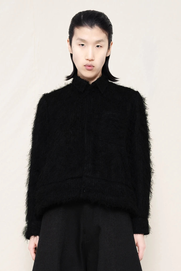 Man-wearing-A-black-COLLARED-HAIRY-JACQUARD-BUTTON-DOWN-WITH-FOAM-BOTTOM-DETAIL-over-wide-black-trousers-against-a-plain-background-front-view