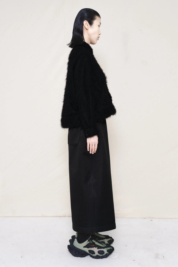 Man-wearing-A-black-COLLARED-HAIRY-JACQUARD-BUTTON-DOWN-WITH-FOAM-BOTTOM-DETAIL-over-wide-black-trousers-and-custom-shoes-against-a-plain-background-full-body-side-view