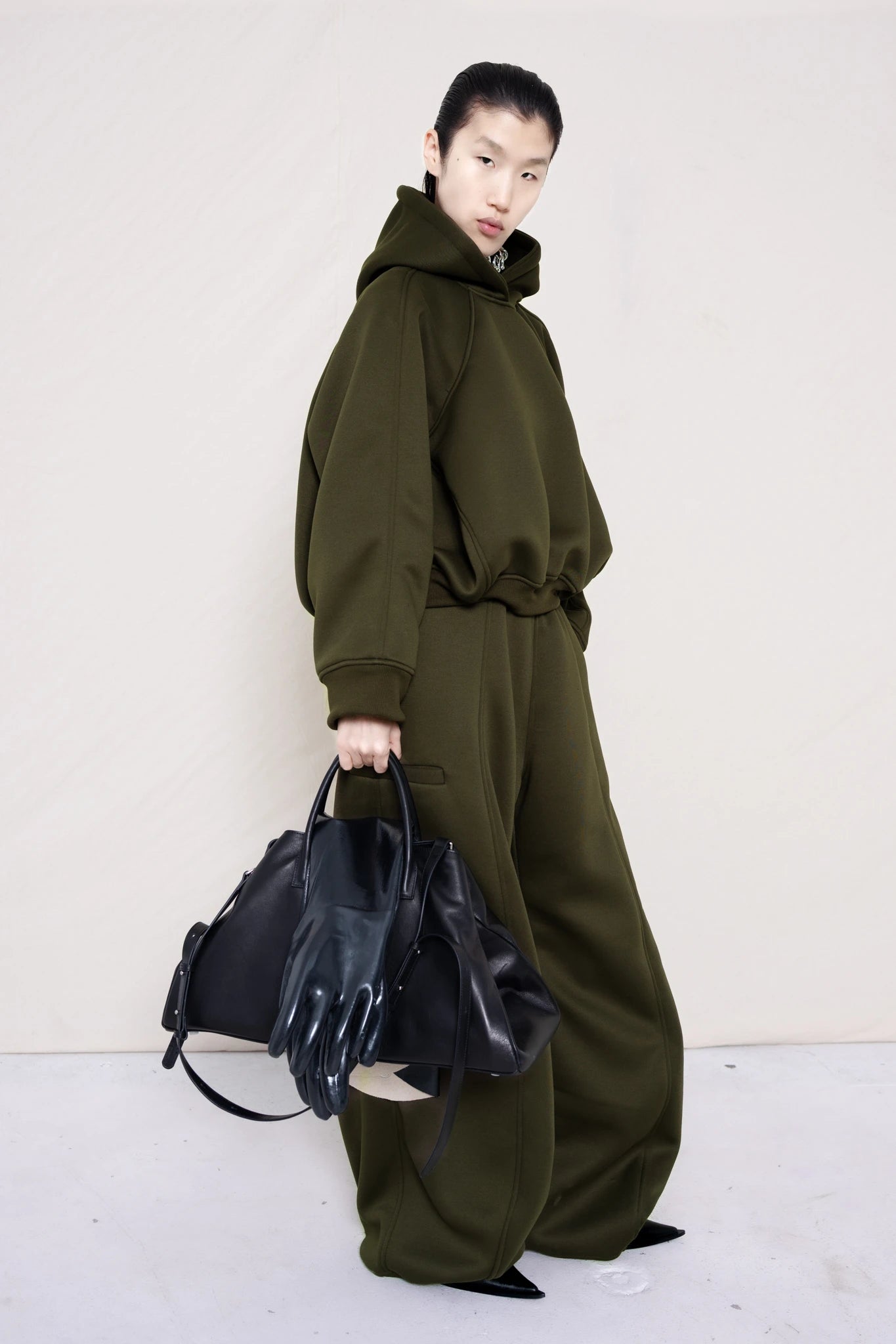 PERSON-WEARING-MOSS-CROPPED-HOODIE-WITH-MATCHING-MOSS-ROUND-LEG-LOUNGEPANTS-AND-BLACK-FLAT-POINTY-BOOTS-HOLDING-BLACK-COWHIDE-A-LINE-SHOPPER-BAG-THREE-QUARTER-VIEW