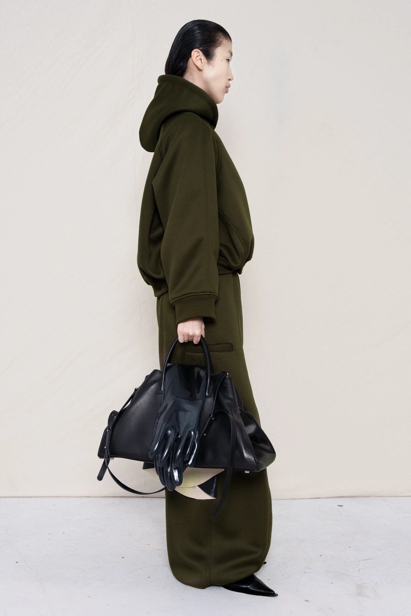 PERSON-WEARING-MOSS-CROPPED-HOODIE-WITH-MATCHING-MOSS-ROUND-LEG-LOUNGEPANTS-AND-BLACK-FLAT-POINTY-BOOTS-HOLDING-BLACK-COWHIDE-A-LINE-SHOPPER-BAG-SIDE-VIEW