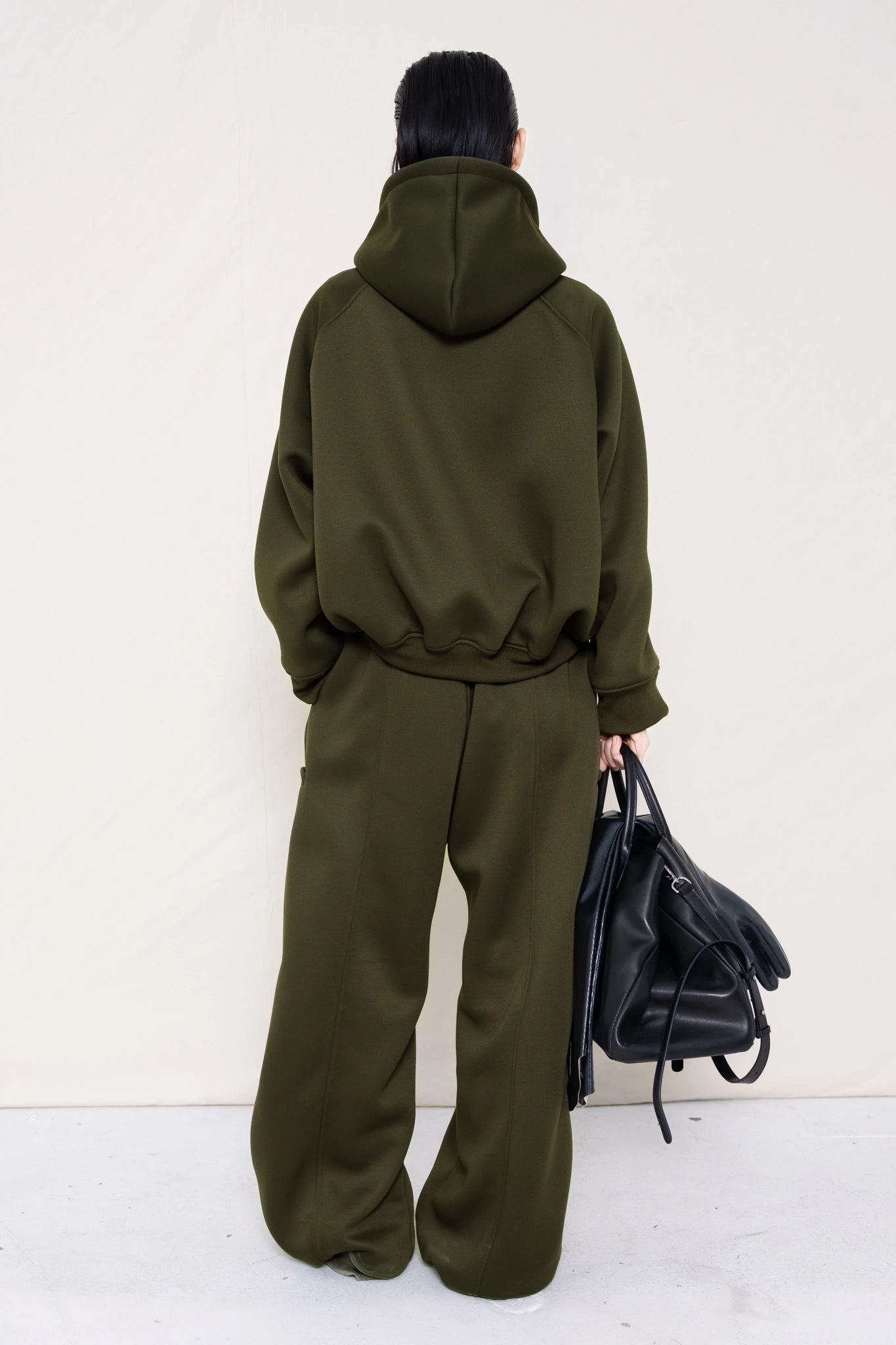 PERSON-WEARING-MOSS-CROPPED-HOODIE-WITH-MATCHING-MOSS-ROUND-LEG-LOUNGEPANTS-AND-BLACK-FLAT-POINTY-BOOTS-HOLDING-BLACK-COWHIDE-A-LINE-SHOPPER-BAG-BACK-VIEW