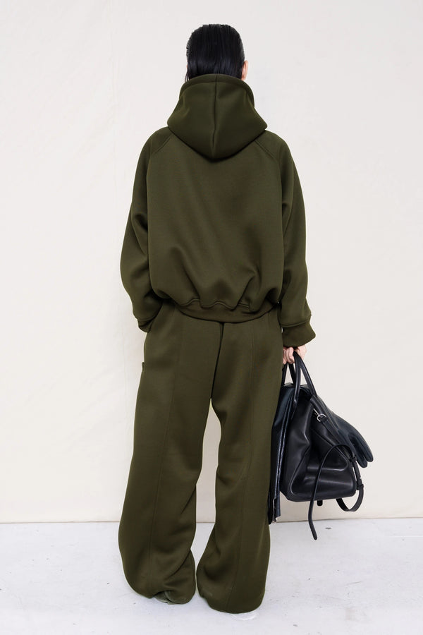 PERSON-WEARING-MOSS-CROPPED-HOODIE-WITH-MATCHING-MOSS-ROUND-LEG-LOUNGEPANTS-AND-BLACK-FLAT-POINTY-BOOTS-HOLDING-BLACK-COWHIDE-A-LINE-SHOPPER-BAG-BACK-VIEW