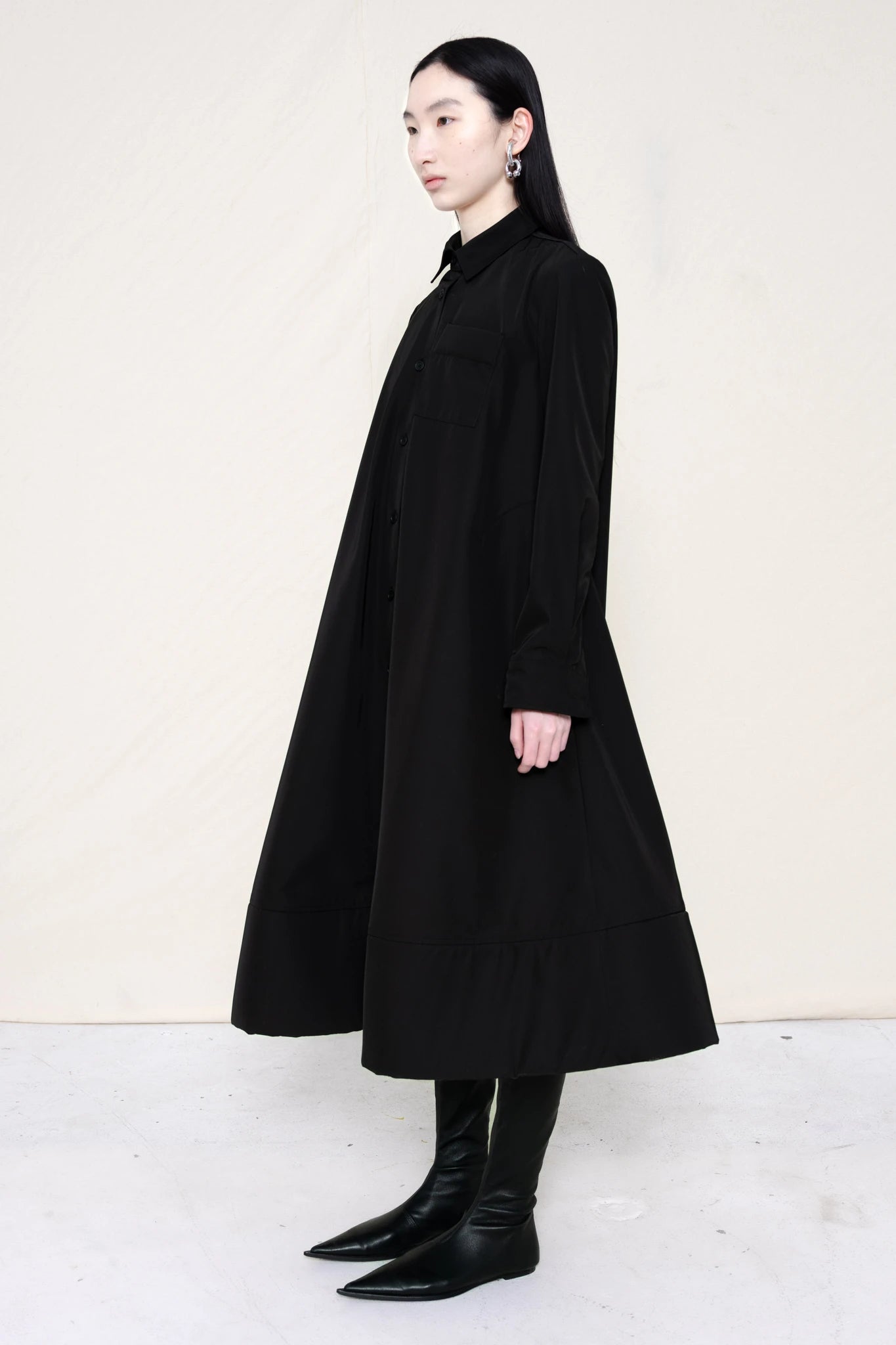 PERSON-WEARING-BLACK-COLLARED-FOAM-BOTTOM-BUTTON-DOWN-SHIRT-DRESS-WITH-BLACK-FLAT-POINTY-BOOTS-THREE-QUARTER-VIEW