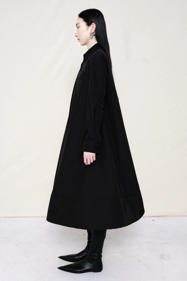 PERSON-WEARING-BLACK-COLLARED-FOAM-BOTTOM-BUTTON-DOWN-SHIRT-DRESS-WITH-BLACK-FLAT-POINTY-BOOTS-SIDE-VIEW