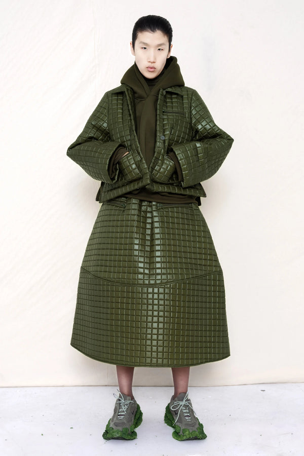 PERSON-WEARING-MOSS-GREEN-COLORED-QUILTED-JACKET-WITH-POCKETS-AND-COLLAR-OVER-MOSS-GREEN-HOODIE-WITH-MATCHING-QUILTED-A-LINE-SKIRT-AND-MUD-GREEN-COLORED-CUSTOMIZED-NIKE-SNEAKER-FRONT-VIEW