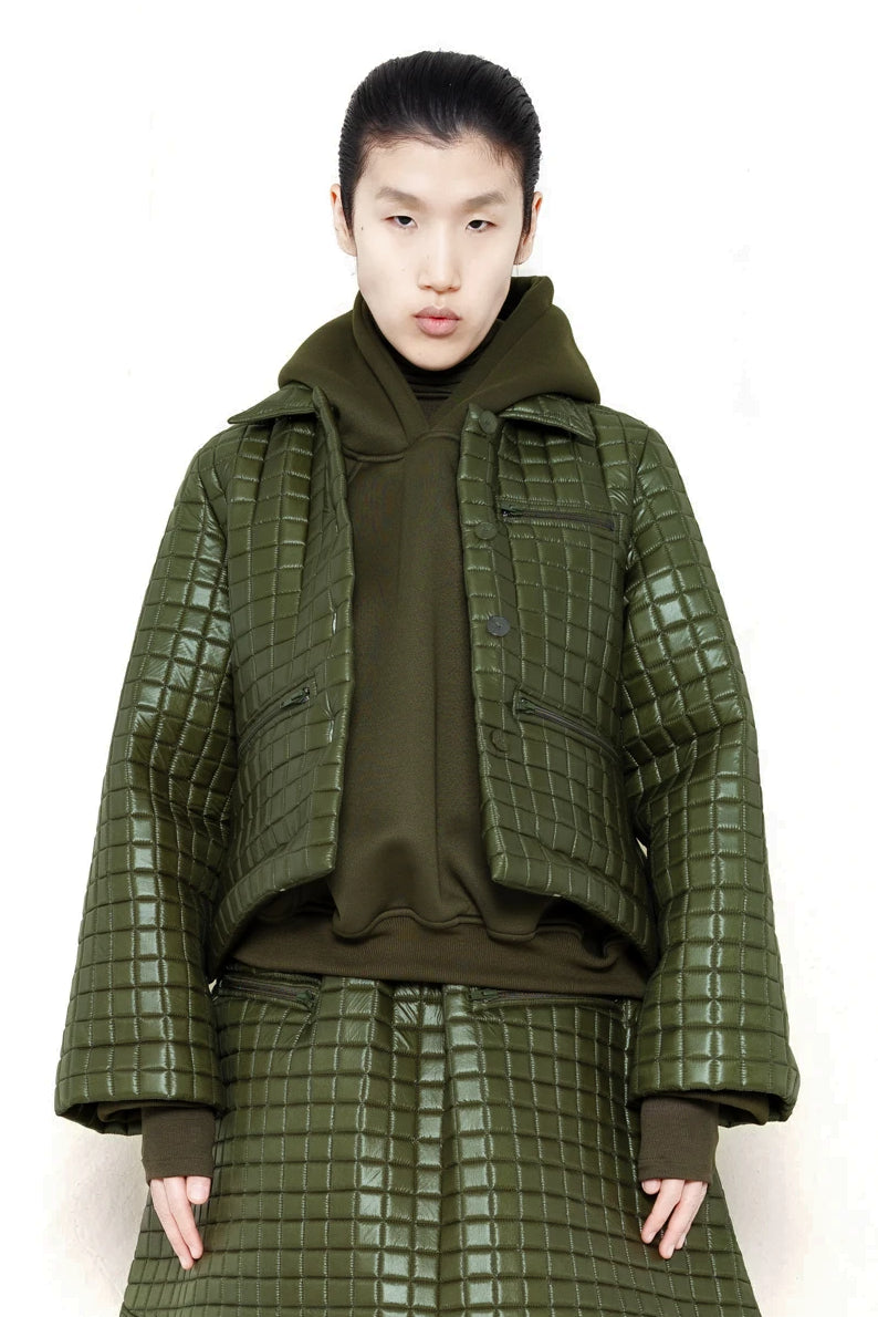 PERSON-WEARING-MOSS-GREEN-COLORED-QUILTED-JACKET-WITH-POCKETS-AND-COLLAR-OVER-MOSS-GREEN-HOODIE-WITH-MATCHING-QUILTED-A-LINE-SKIRT-AND-MUD-GREEN-COLORED-CUSTOMIZED-NIKE-SNEAKER-FRONT-VIEW