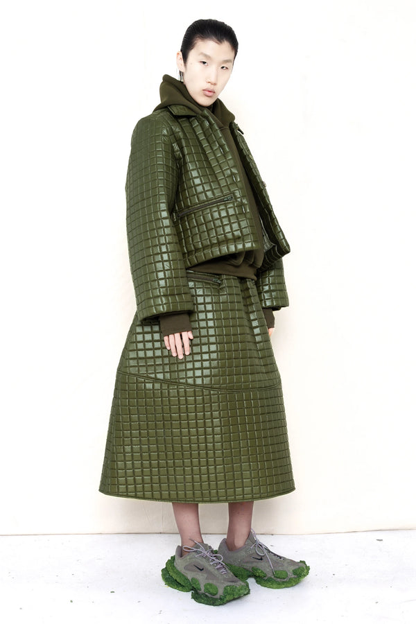 PERSON-WEARING-MOSS-GREEN-COLORED-QUILTED-JACKET-WITH-POCKETS-AND-COLLAR-OVER-MOSS-GREEN-HOODIE-WITH-MATCHING-QUILTED-A-LINE-SKIRT-AND-MUD-GREEN-COLORED-CUSTOMIZED-NIKE-SNEAKER-QUATER-FRONT-VIEW