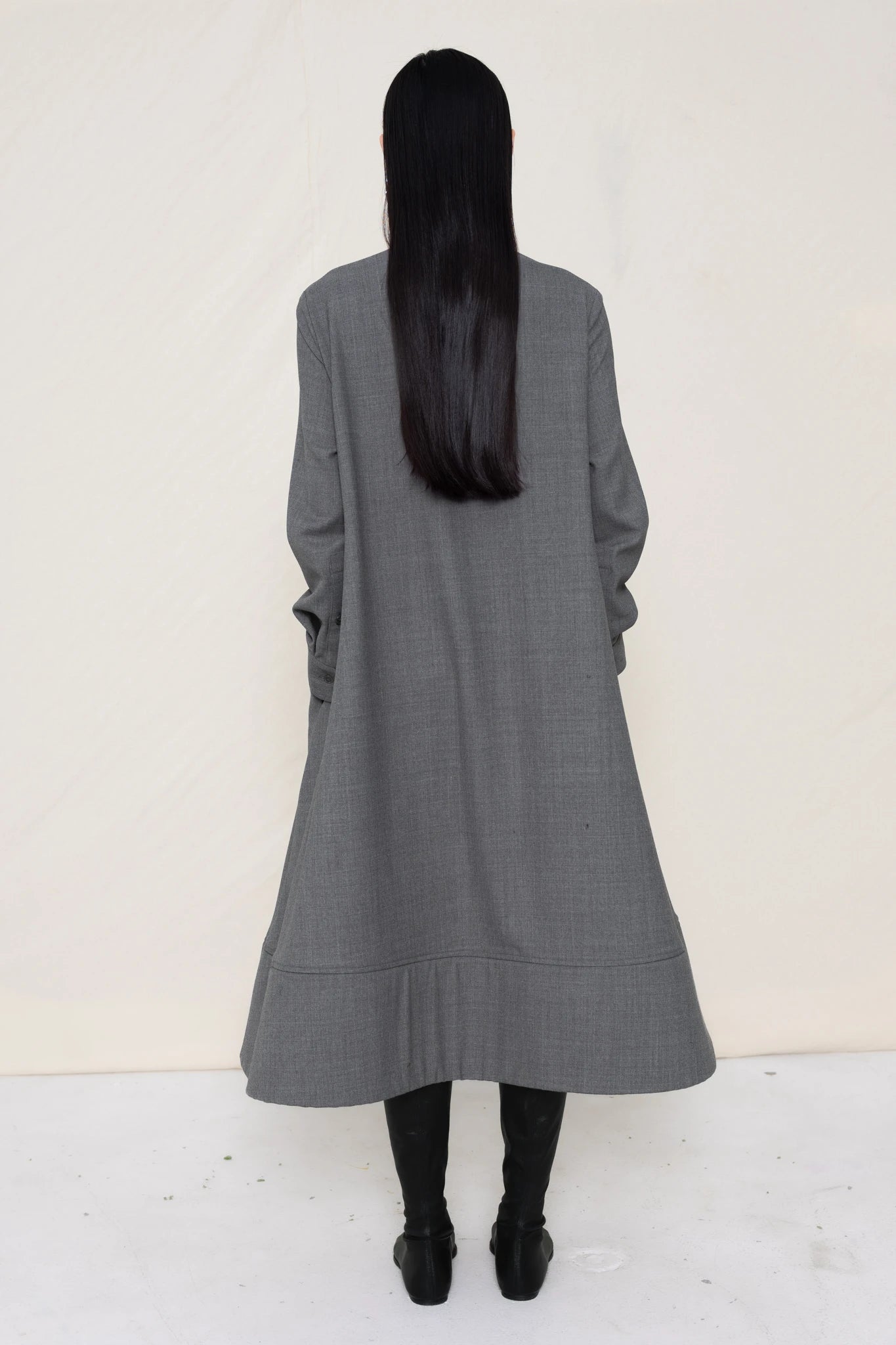 PERSON-WEARING-GREY-COLLARED-FOAM-BOTTOM-BUTTON-DOWN-SHIRT-DRESS-WITH-BLACK-FLAT-POINTY-BOOTS-BACK-VIEW