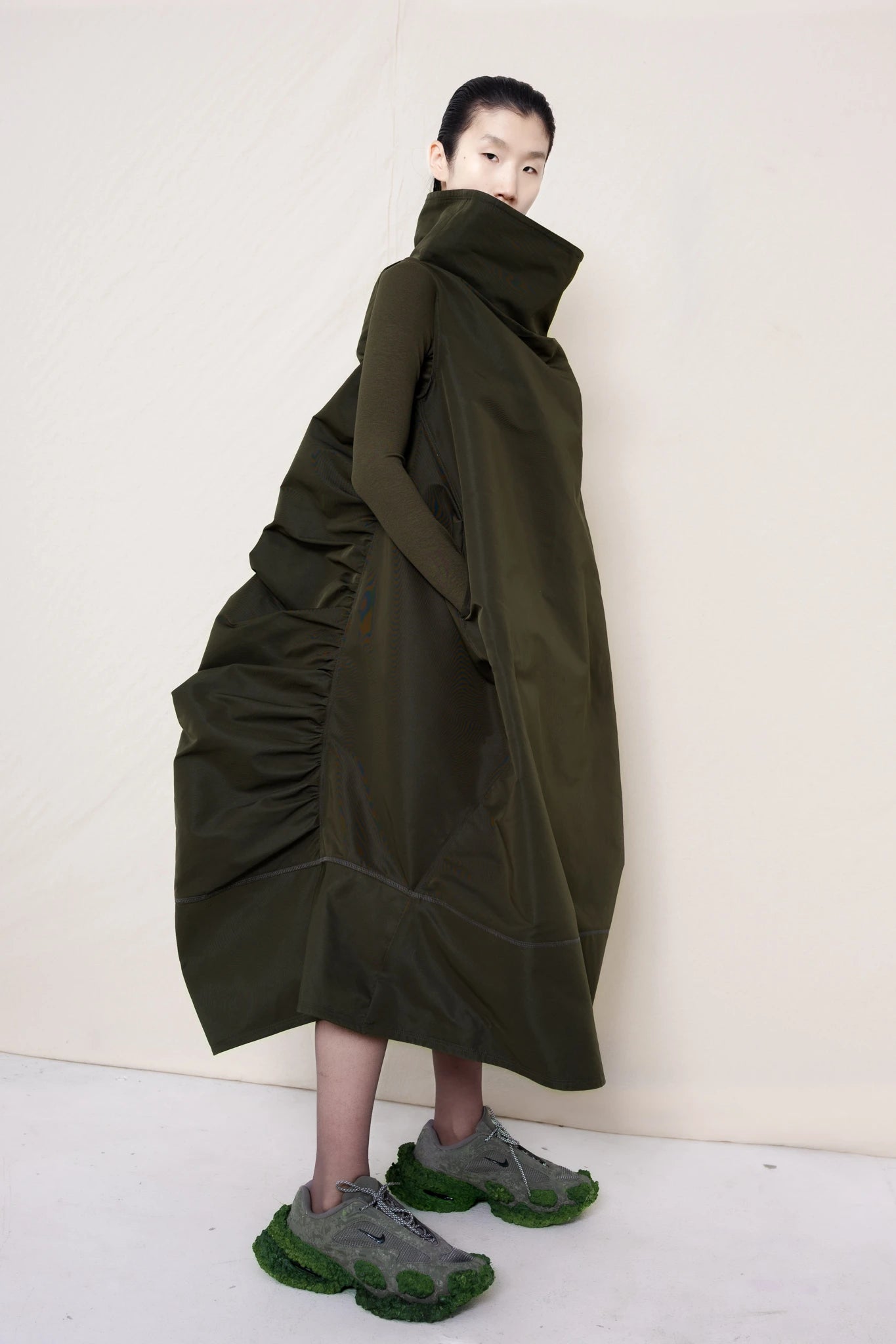 PERSON-WEARING-MOSS-HIGH-COLLAR-DRESS-WITH-RUCHED-BACK-DETAILING-OVER-MATCHING-COLORED-LONGSLEEVE-WITH-CUSTOMIZED-SNEAKERS-THREE-QUARTER-VIEW