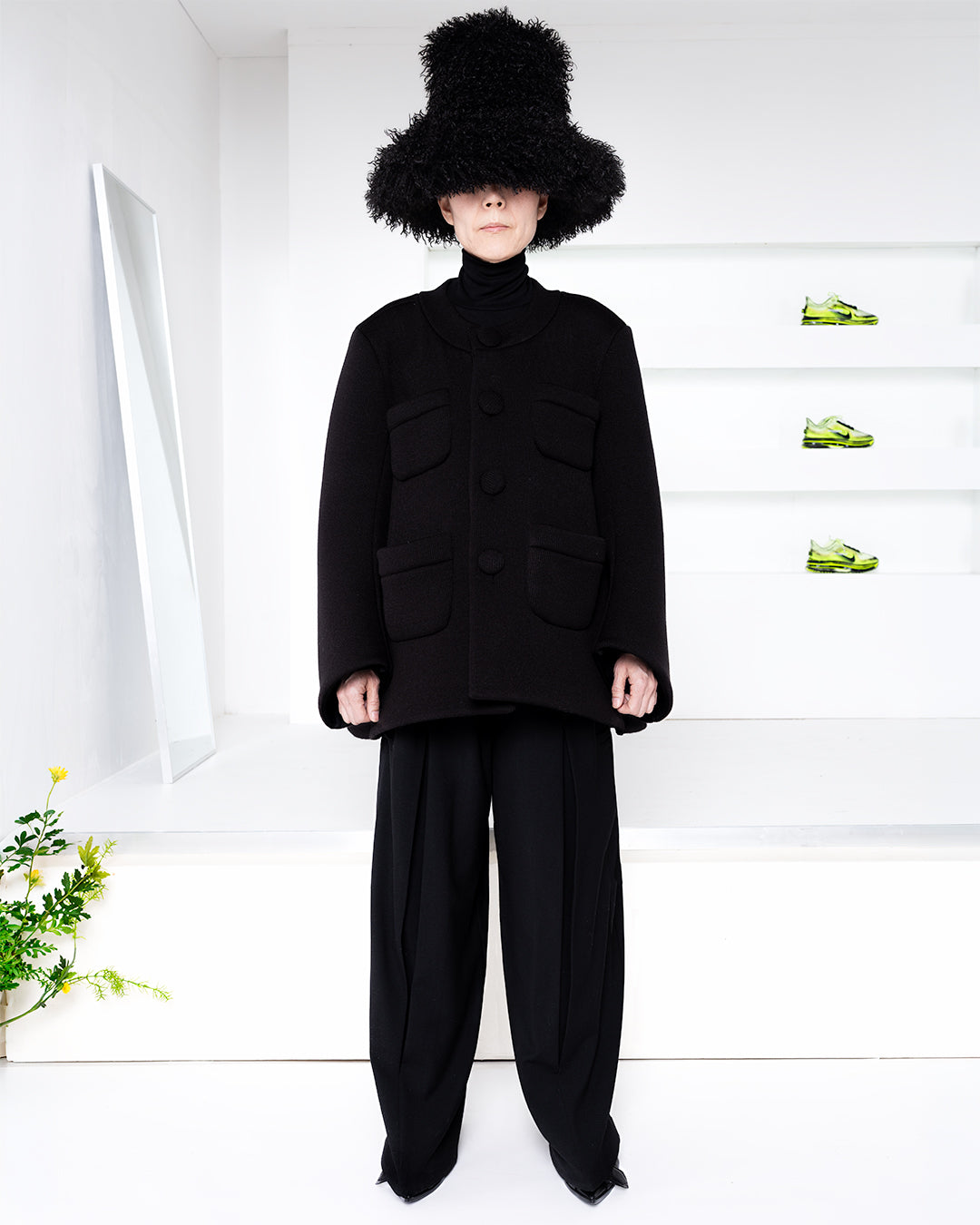 Model wearing an all black outfit with a black bucket hat in a white room