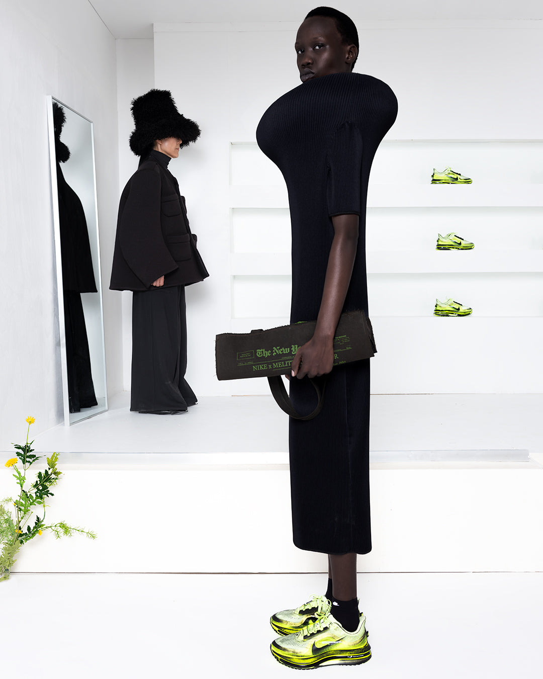Model wearing a black dress in a white room