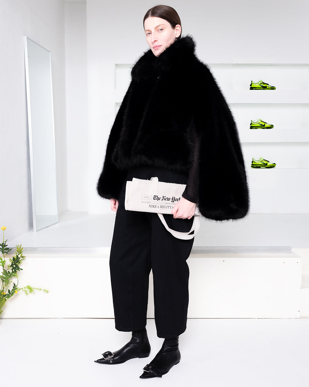 Model wearing a furry coat holding a newspaper tote