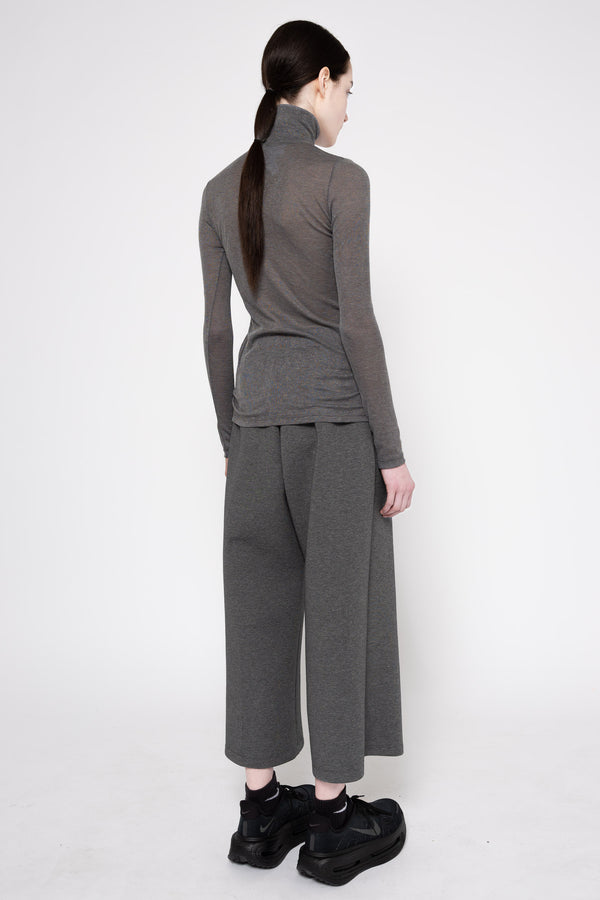 A model shown from the back wearing a dark gray ribbed turtleneck sweater and matching wide-leg cropped pants, paired with black sneakers, against a plain white studio background.