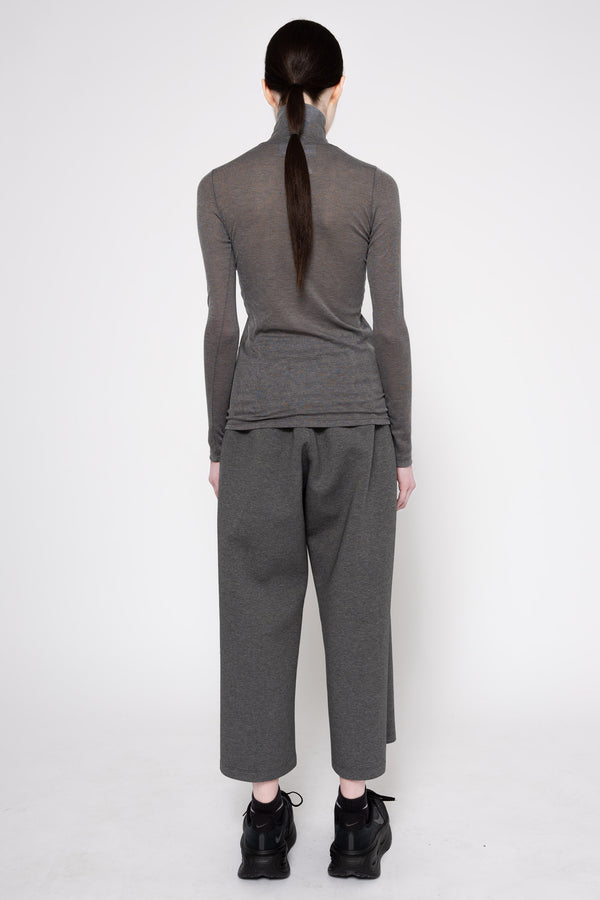 A model shown from the back wearing a dark gray ribbed long-sleeve mock neck top and matching wide-leg cropped pants, paired with black platform sneakers, against a plain white studio background.