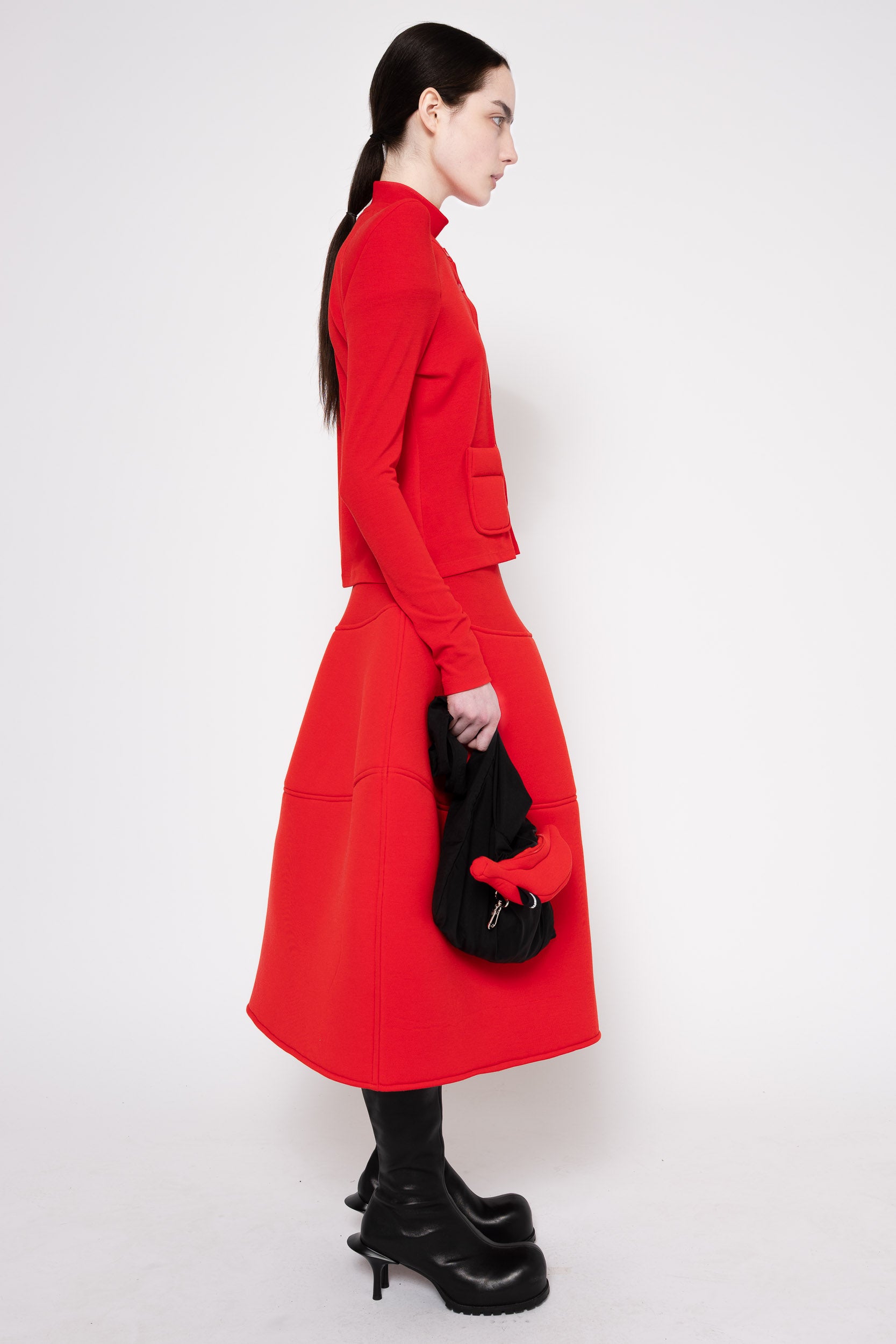 Side view of model wearing bold red cardigan and shaped circle skirt.