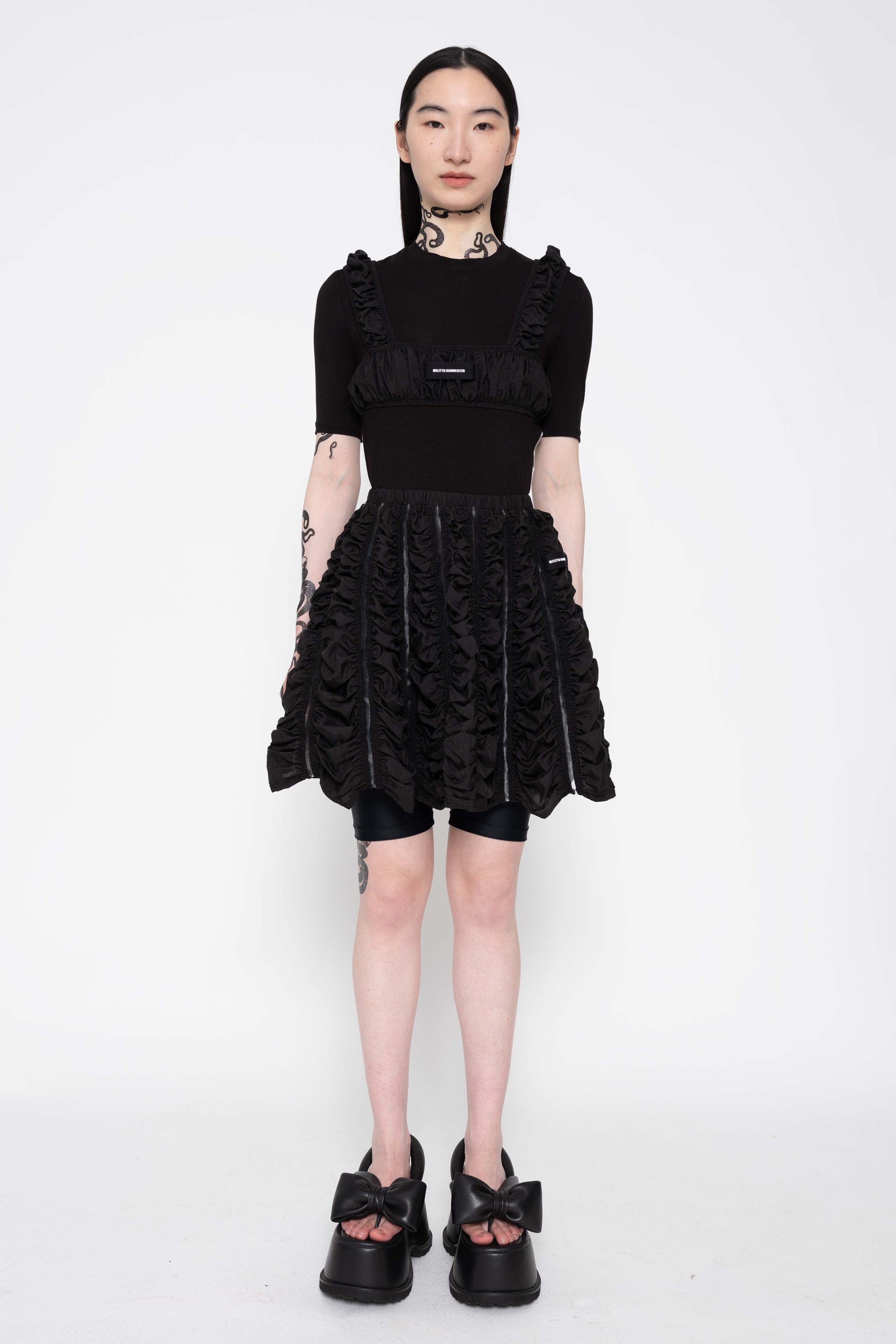 MELITTA-BAUMEISTER-RUCHED-BRA-FULL-BODY-VIEW-WITH-BLACK-SHORT-SKIRT-AND-BLACK-LEATHER-BOW-SHOES